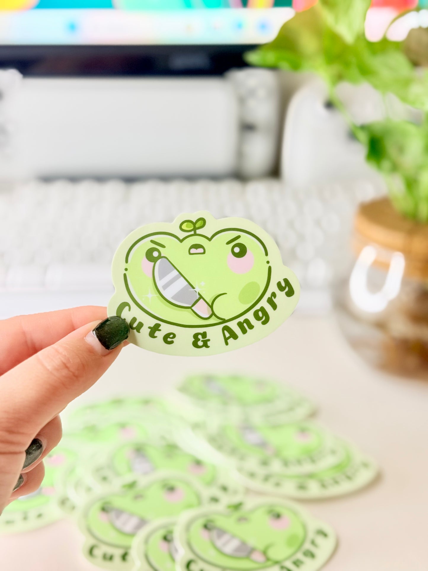 Cute & Angry Frog Vinyl Sticker featuring Light green frog sticker holding a knife with the words ‘Cute & Angry’ in dark green text".