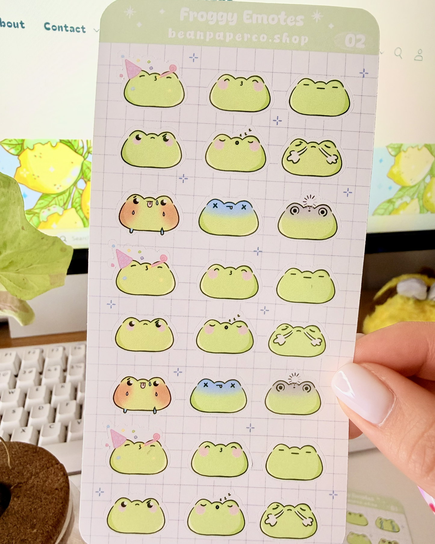 Cute Frog Emote Planner Stickers Vol. 2 featuring cute green frog faces with party hat, blushing, sleepy, angry, shocked, and fainting expressions on a light grid background.”