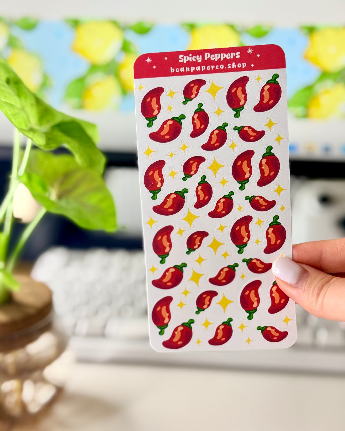 Cute Spicy Peppers Sticker Sheet held by a hand with a computer screen in the background.
