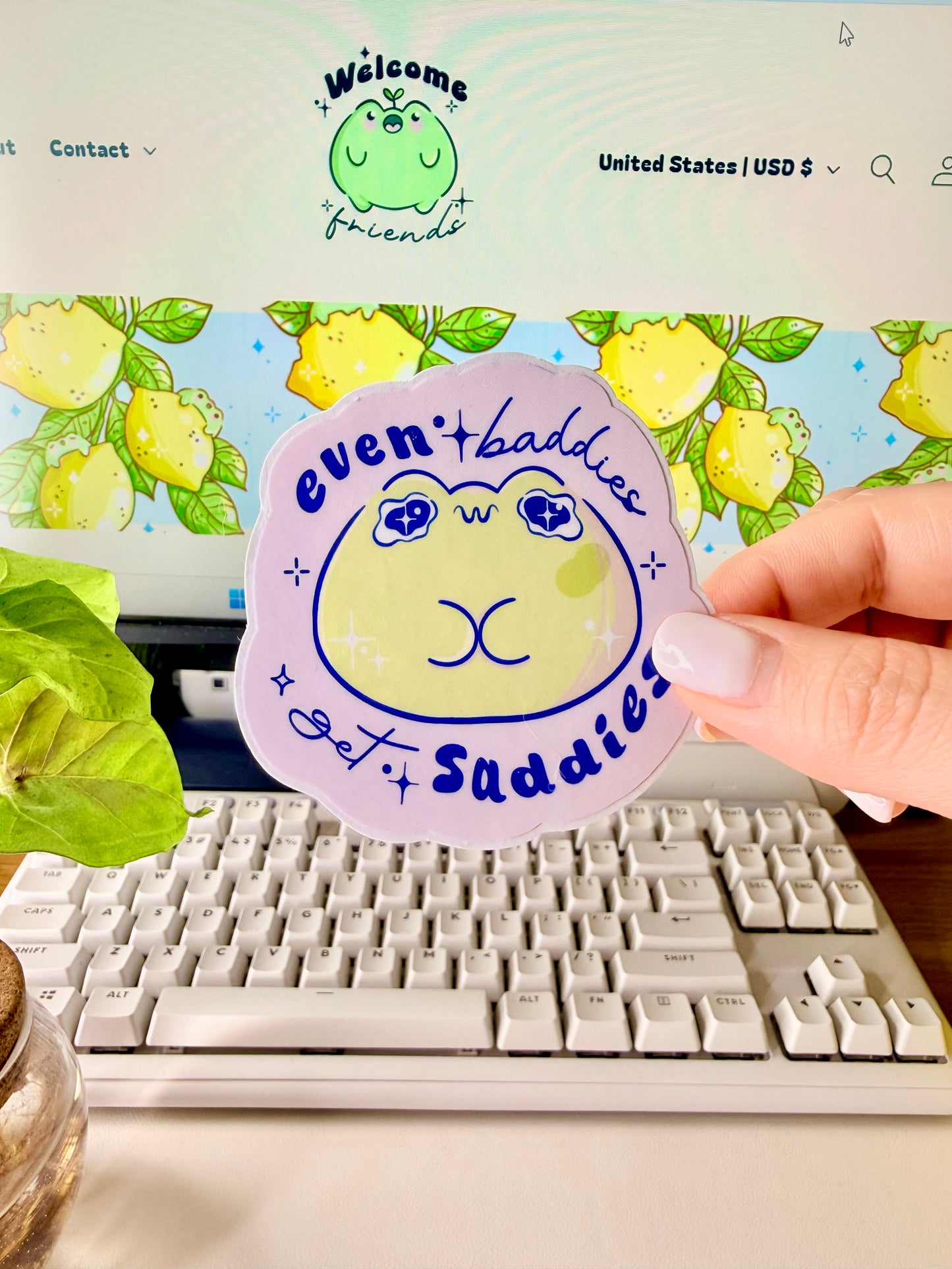 Even Baddies Get Saddies Vinyl Sticker with a cartoon frog character held by a hand in front of a computer screen.
