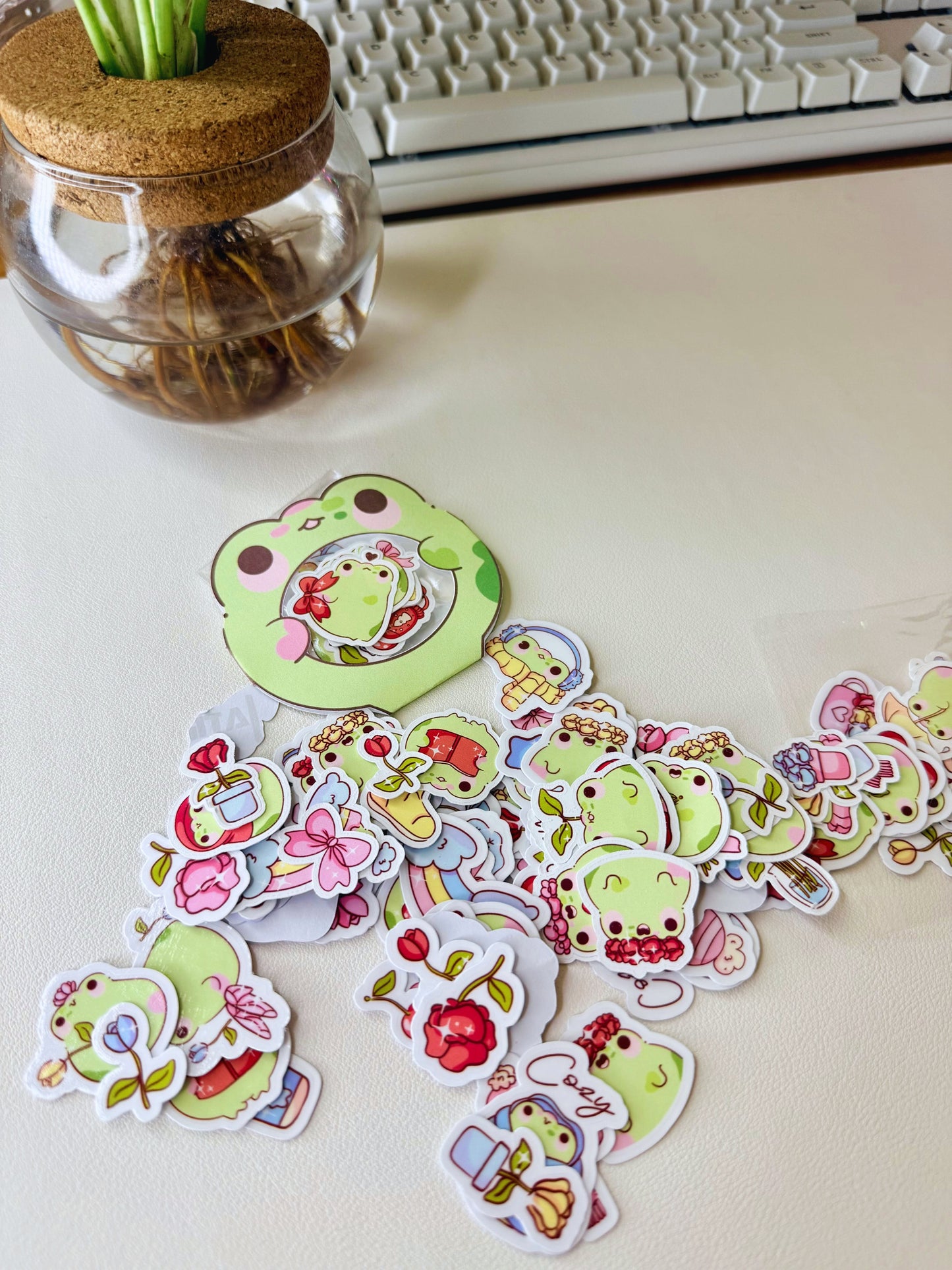 “Cute frog sticker flakes in various seasonal designs spread out on a desk.”