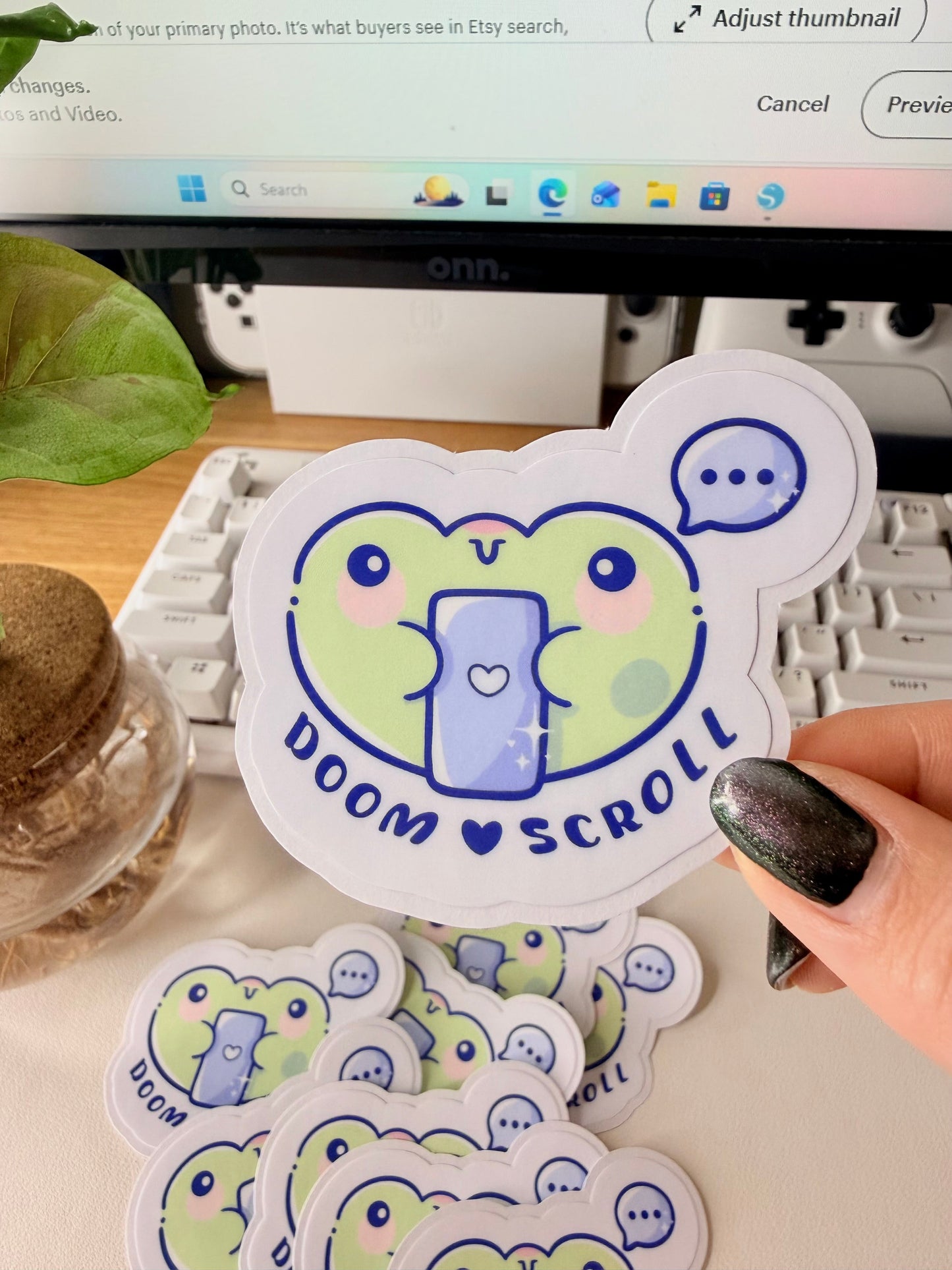 “Cute frog sticker holding a phone with the words ‘Doom Scroll’ underneath and a speech bubble above.”