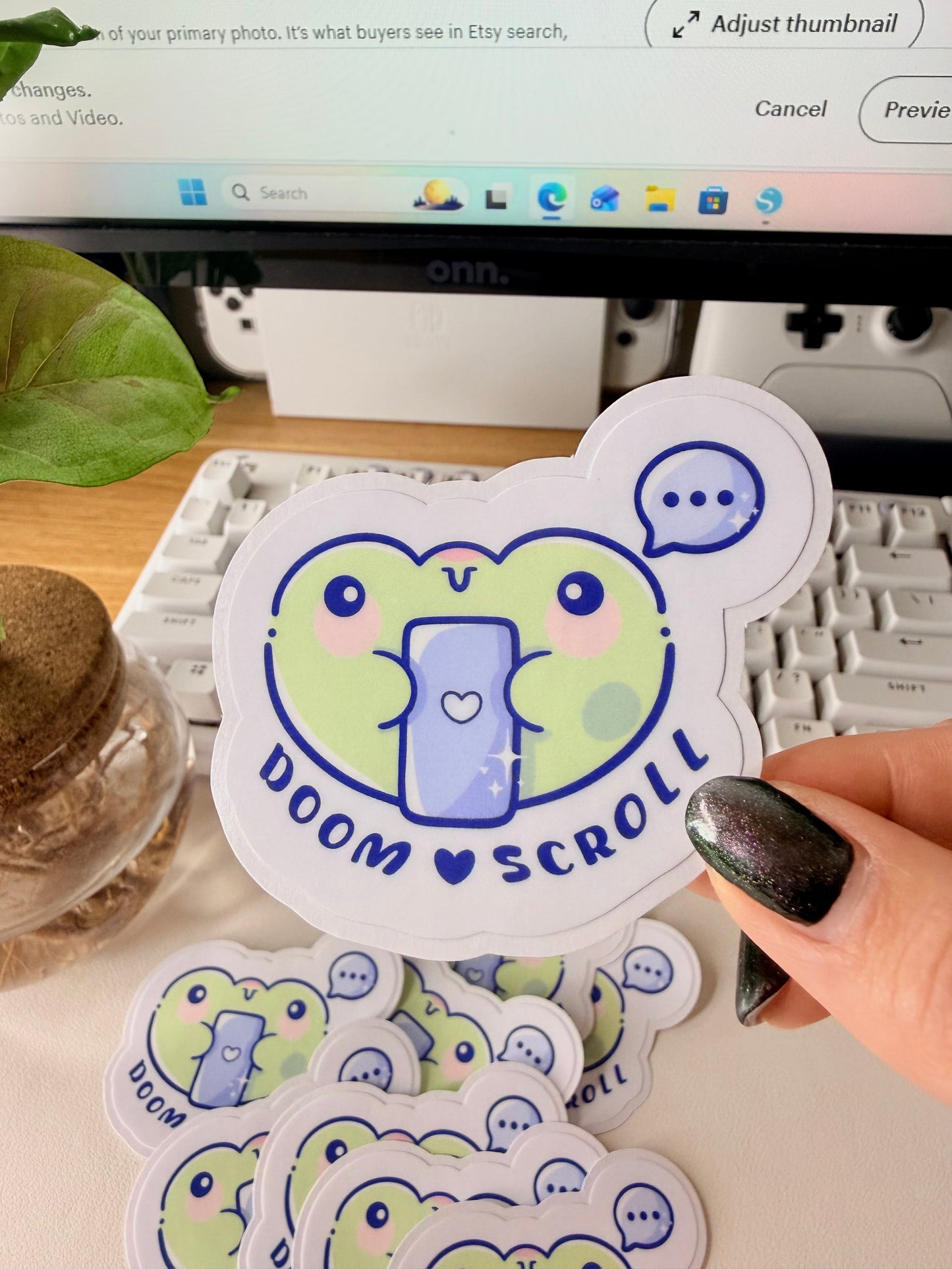 “Cute frog sticker holding a phone with the words ‘Doom Scroll’ underneath and a speech bubble above.”