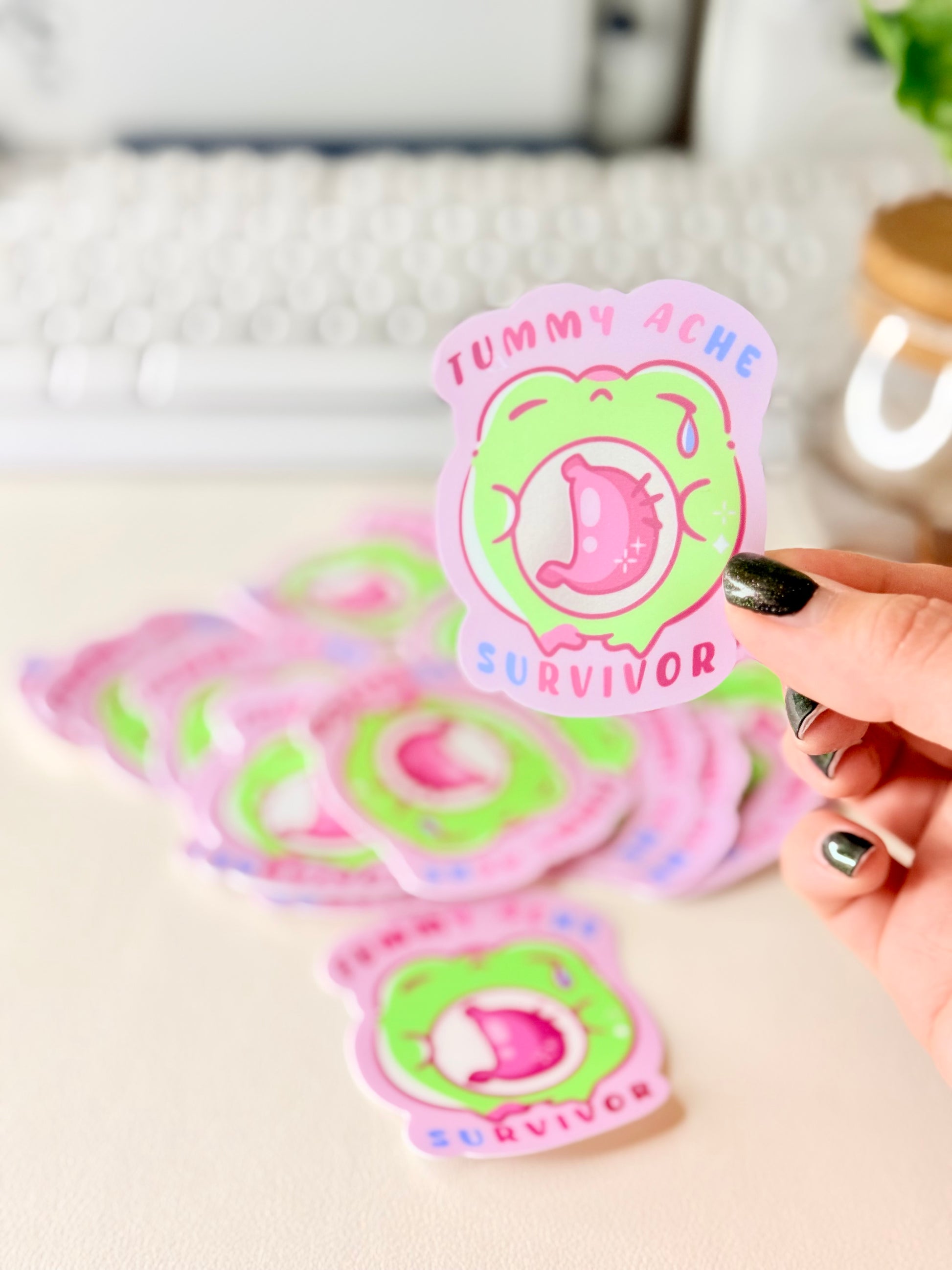 Tummy Ache Survivor Frog Sticker featuring Pastel pink and green frog sticker reading "Tummy Ache Survivor’ with a crying frog holding its stomach".