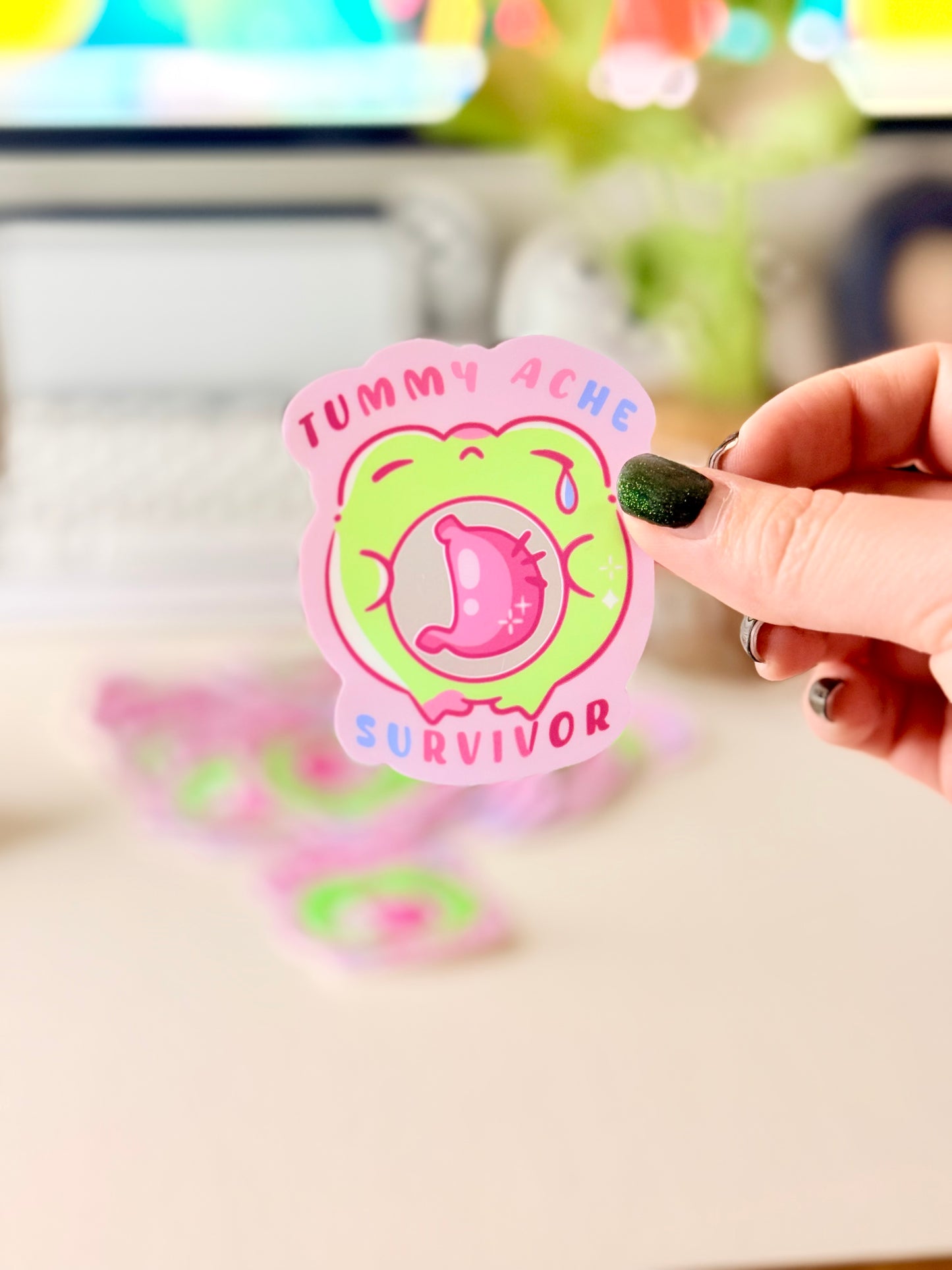 Tummy Ache Survivor Frog Sticker featuring Pastel pink and green frog sticker reading "Tummy Ache Survivor’ with a crying frog holding its stomach".