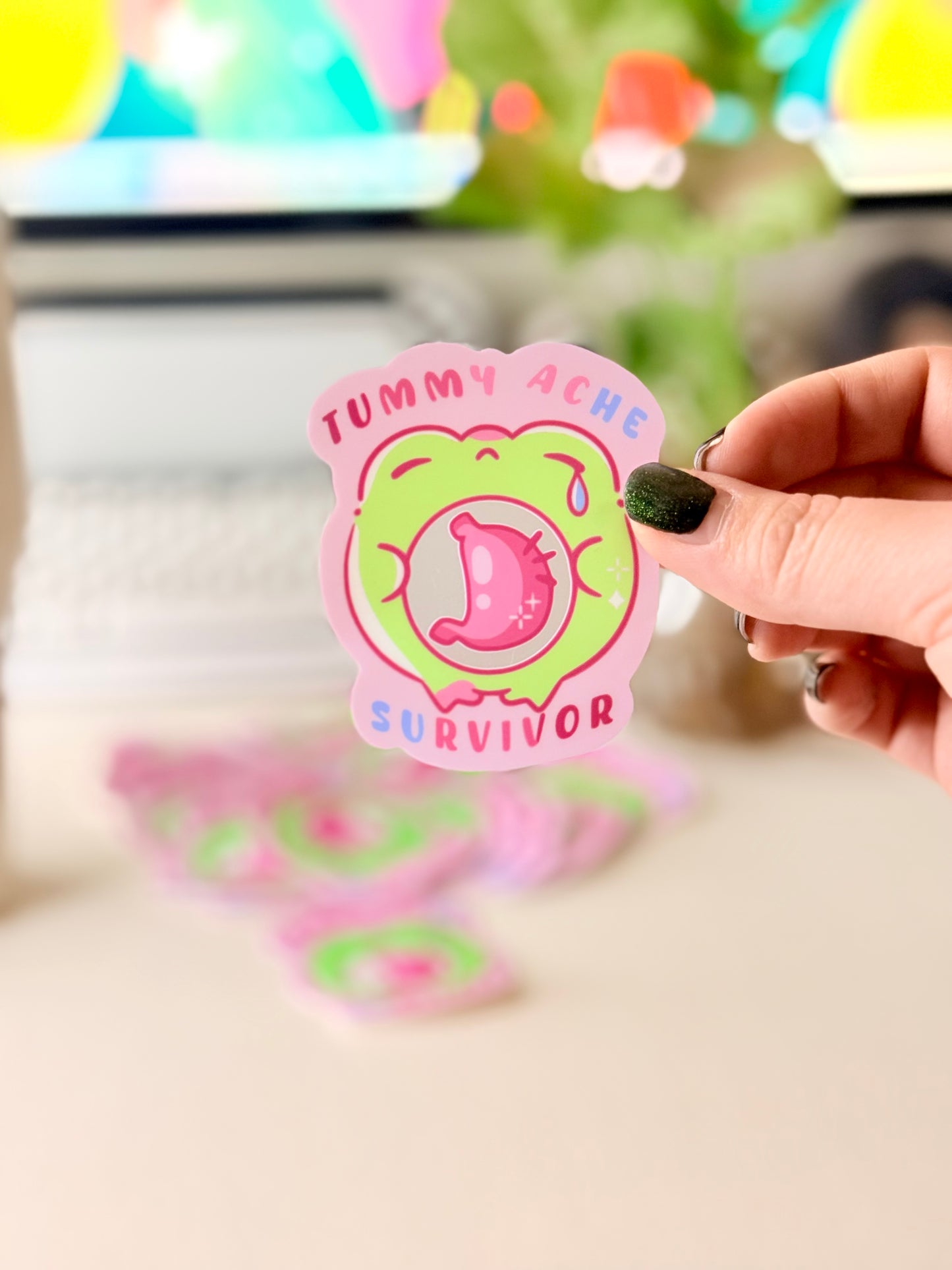Tummy Ache Survivor Frog Sticker featuring Pastel pink and green frog sticker reading "Tummy Ache Survivor’ with a crying frog holding its stomach".