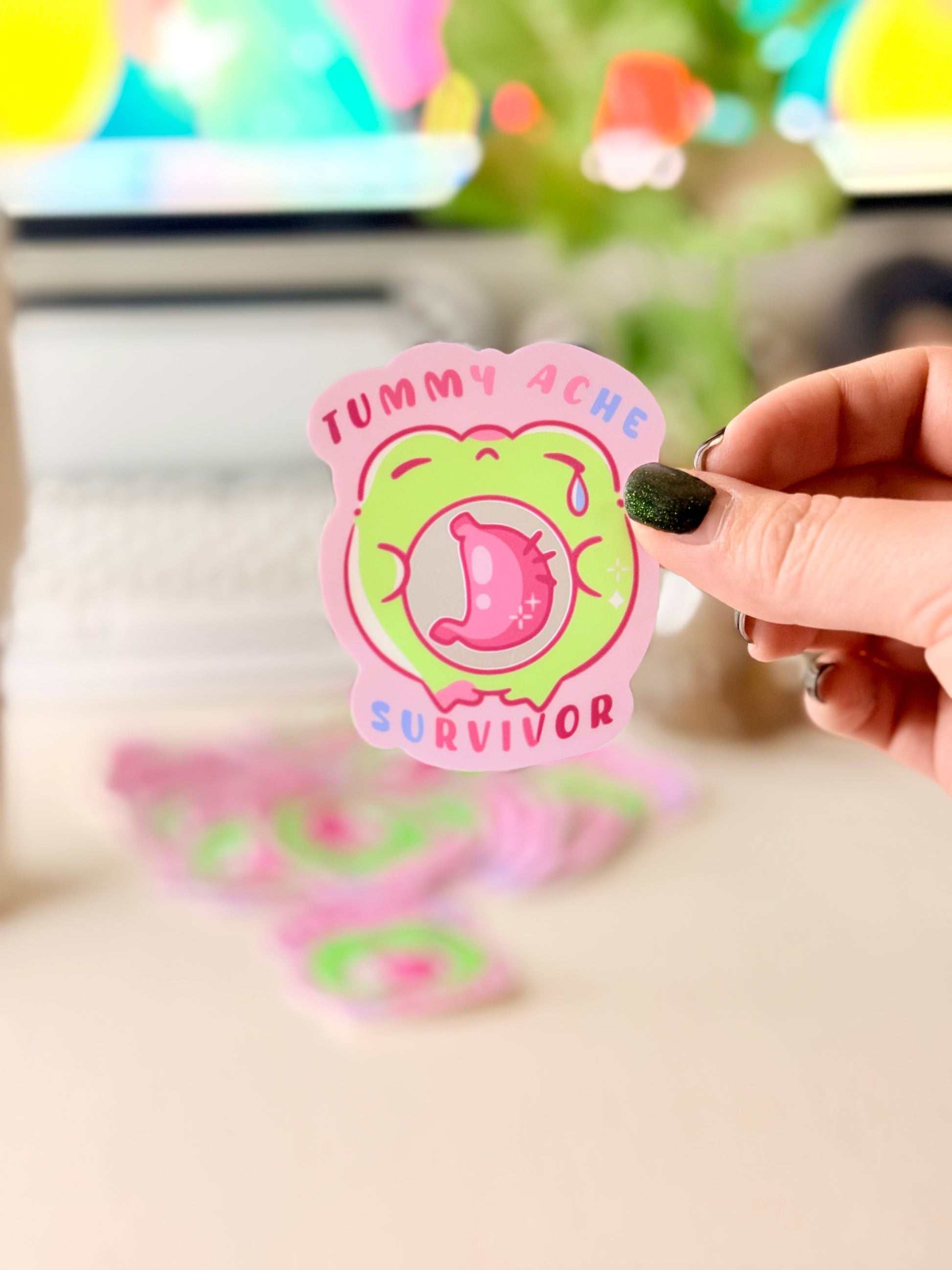 Tummy Ache Survivor Frog Sticker featuring Pastel pink and green frog sticker reading "Tummy Ache Survivor’ with a crying frog holding its stomach".