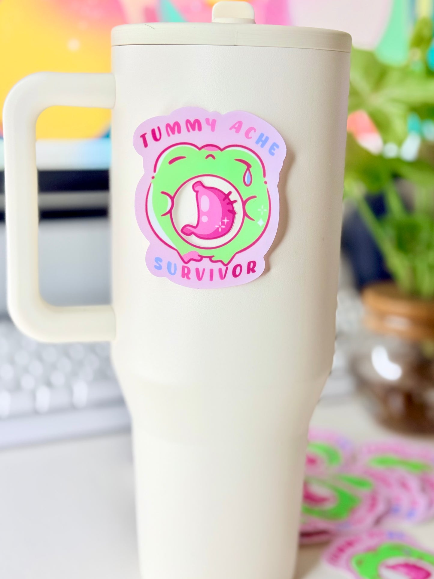 Tummy Ache Survivor Frog Sticker featuring Pastel pink and green frog sticker reading "Tummy Ache Survivor’ with a crying frog holding its stomach".