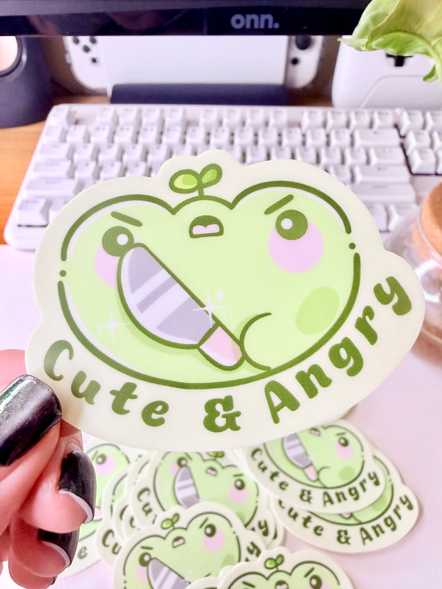 Cute & Angry Frog Vinyl Sticker featuring Light green frog sticker holding a knife with the words ‘Cute & Angry’ in dark green text".
