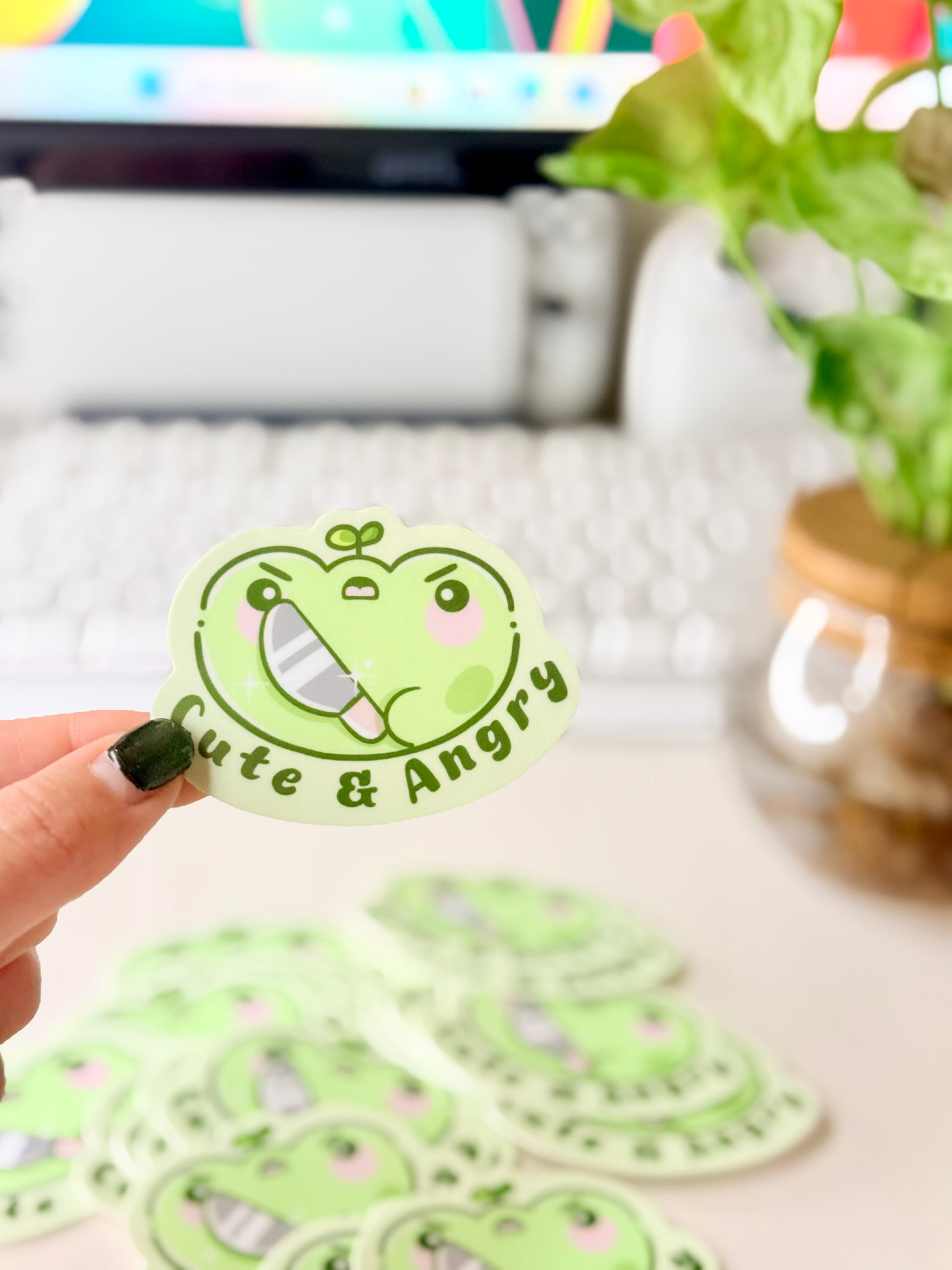 Cute & Angry Frog Vinyl Sticker featuring Light green frog sticker holding a knife with the words ‘Cute & Angry’ in dark green text".