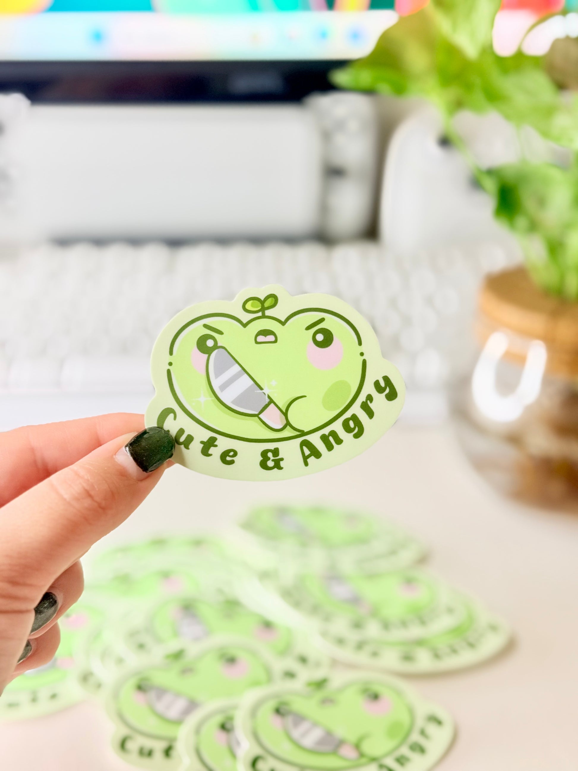 Cute & Angry Frog Vinyl Sticker featuring Light green frog sticker holding a knife with the words ‘Cute & Angry’ in dark green text".