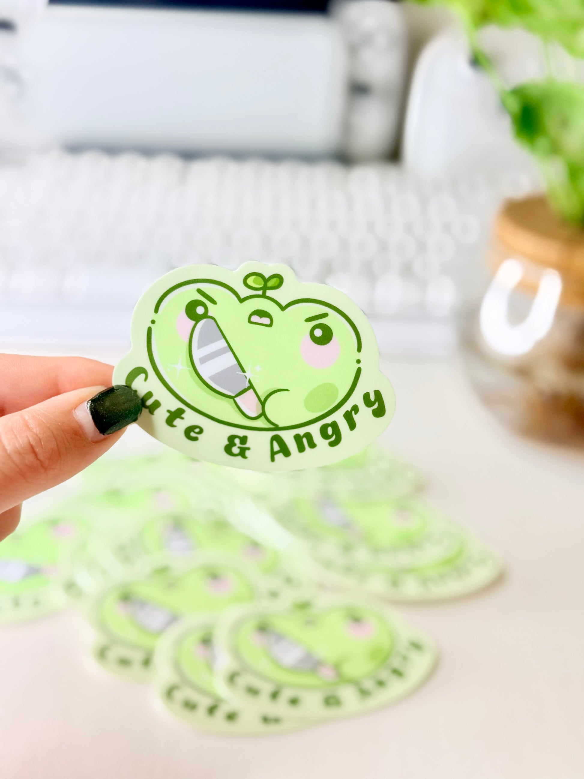 Cute & Angry Frog Vinyl Sticker featuring Light green frog sticker holding a knife with the words ‘Cute & Angry’ in dark green text".