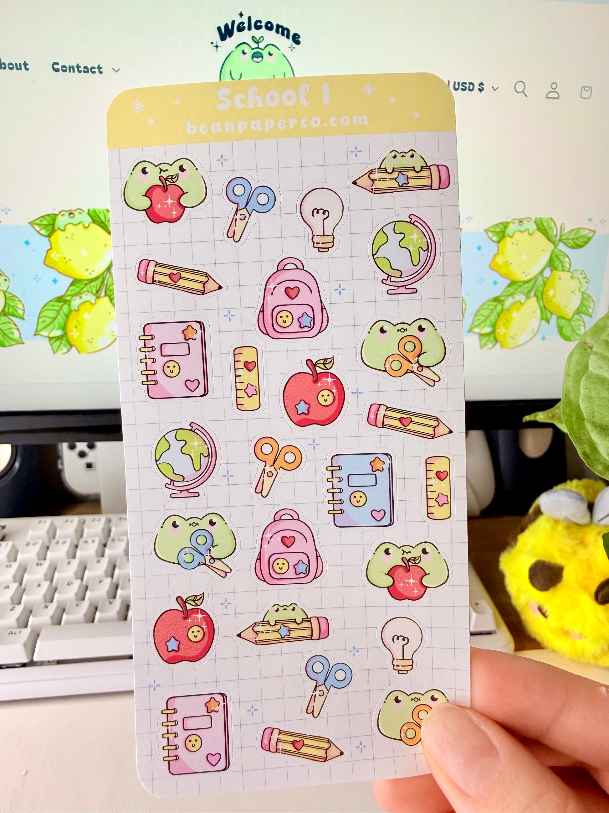 “School-themed frog sticker sheet featuring cute frogs with apples, pencils, scissors, backpacks, notebooks, rulers, and globes on a light grid background.”
