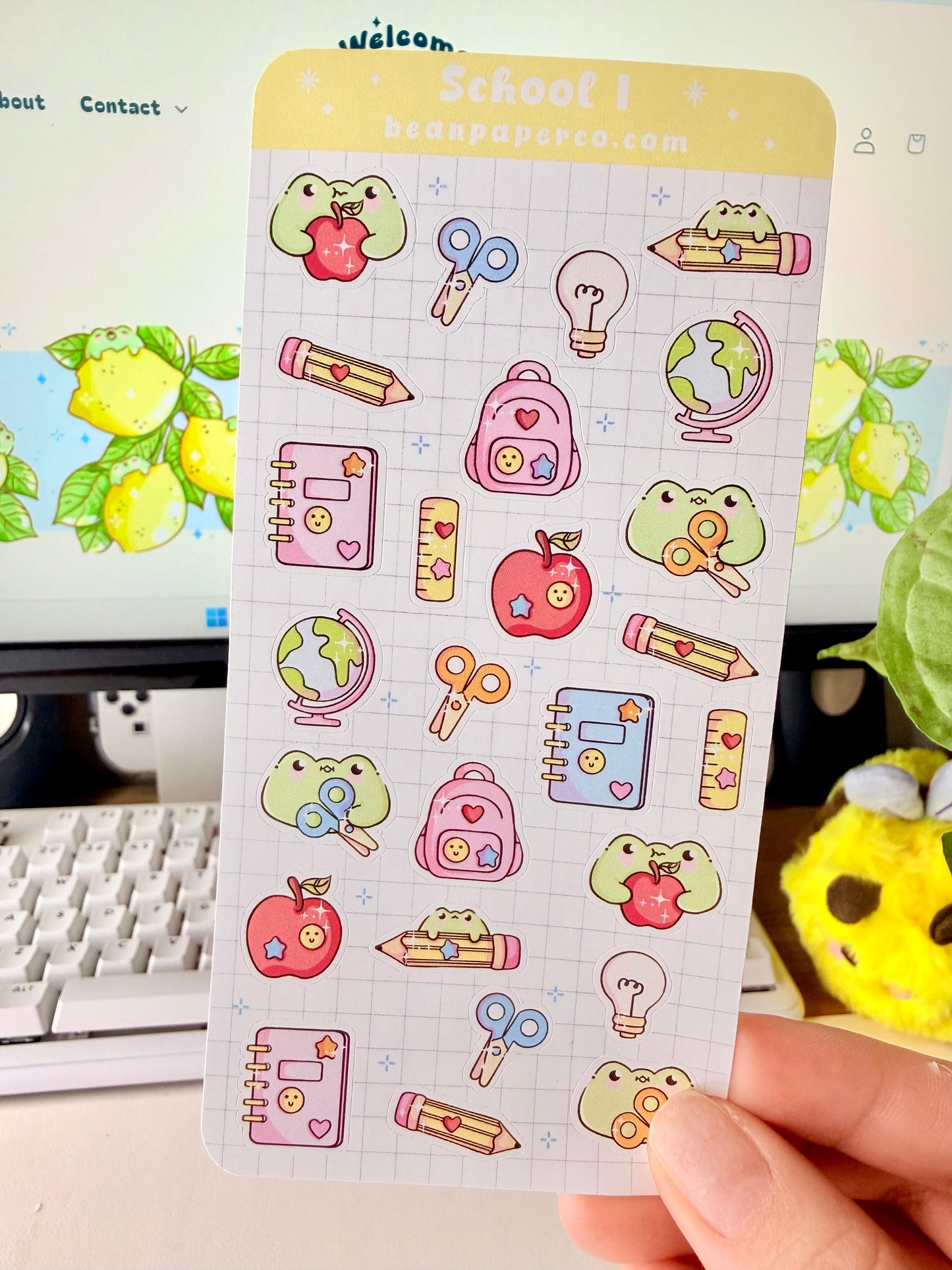 “School-themed frog sticker sheet featuring cute frogs with apples, pencils, scissors, backpacks, notebooks, rulers, and globes on a light grid background.”