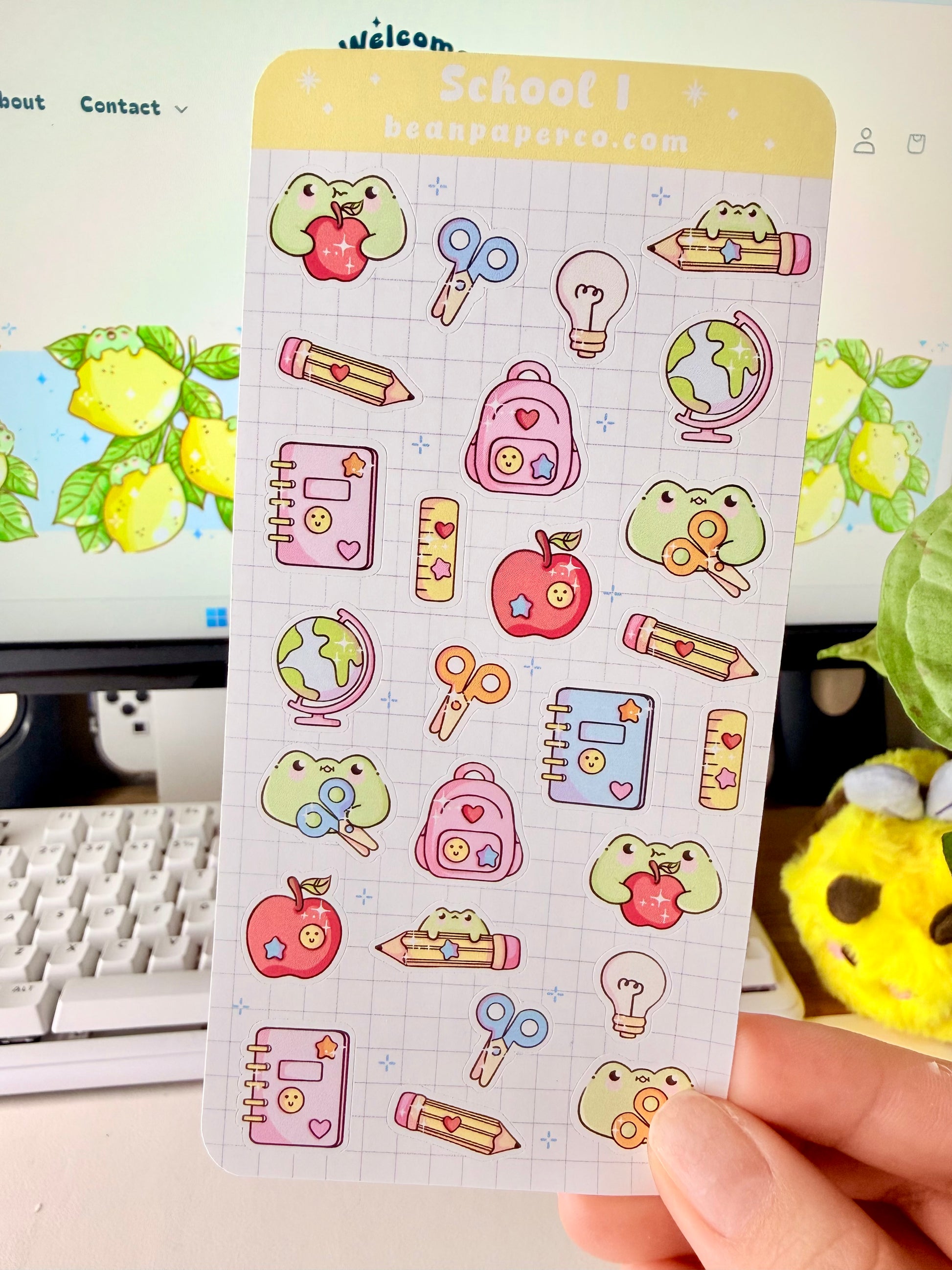 “School-themed frog sticker sheet featuring cute frogs with apples, pencils, scissors, backpacks, notebooks, rulers, and globes on a light grid background.”