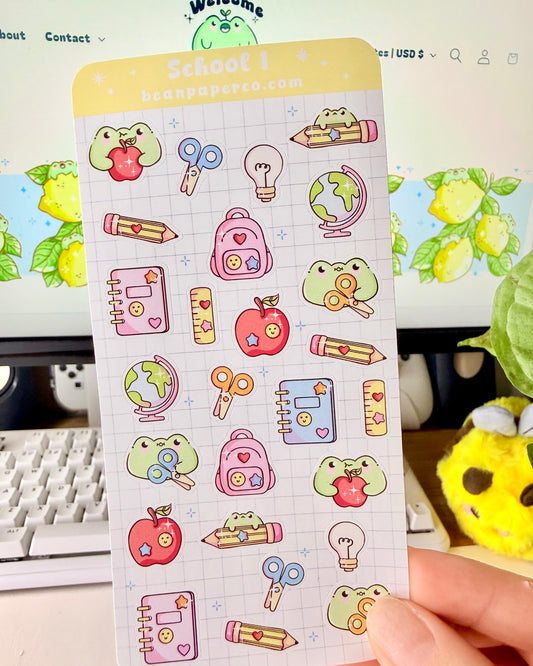 “School-themed frog sticker sheet featuring cute frogs with apples, pencils, scissors, backpacks, notebooks, rulers, and globes on a light grid background.”