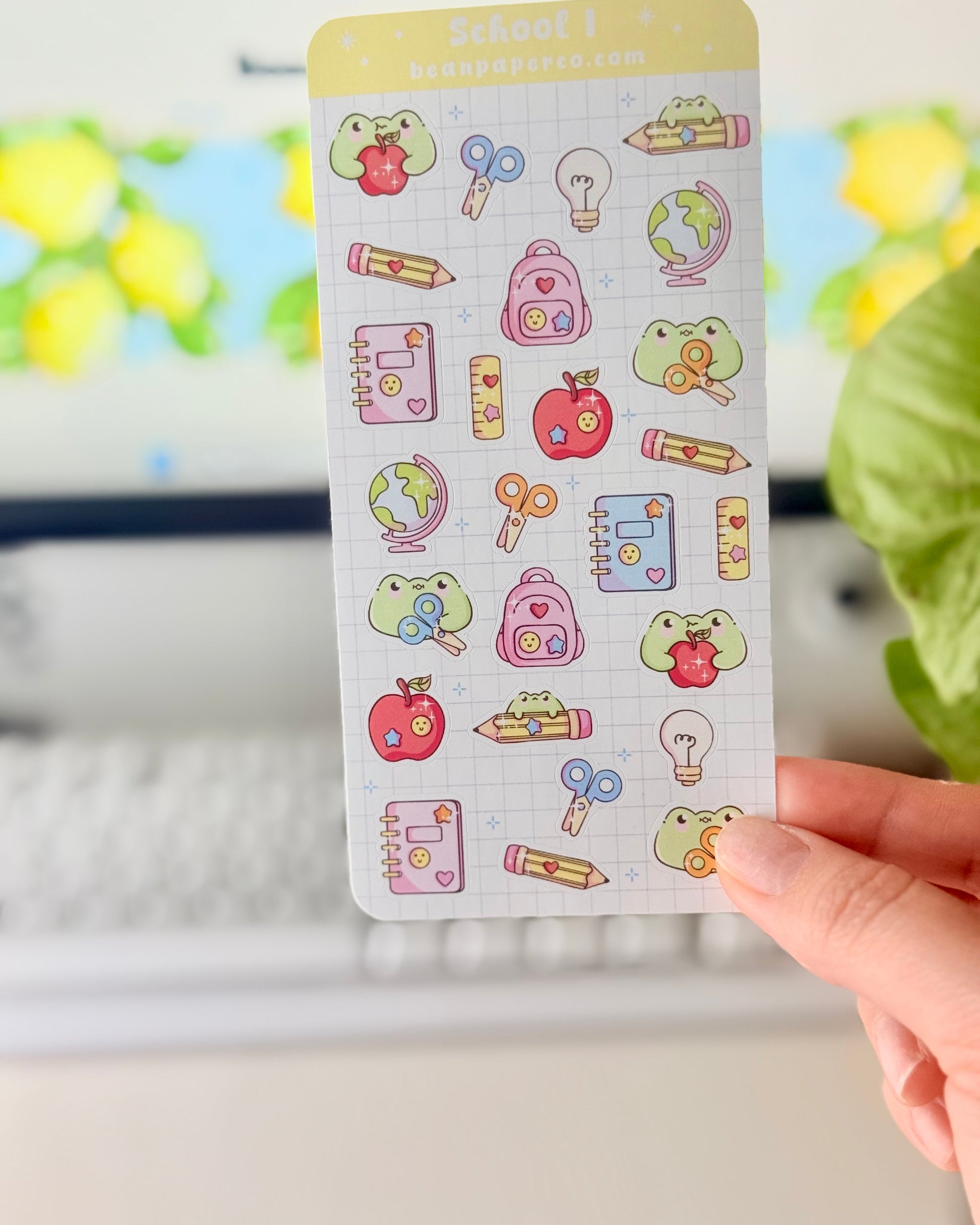 “School-themed frog sticker sheet featuring cute frogs with apples, pencils, scissors, backpacks, notebooks, rulers, and globes on a light grid background.”