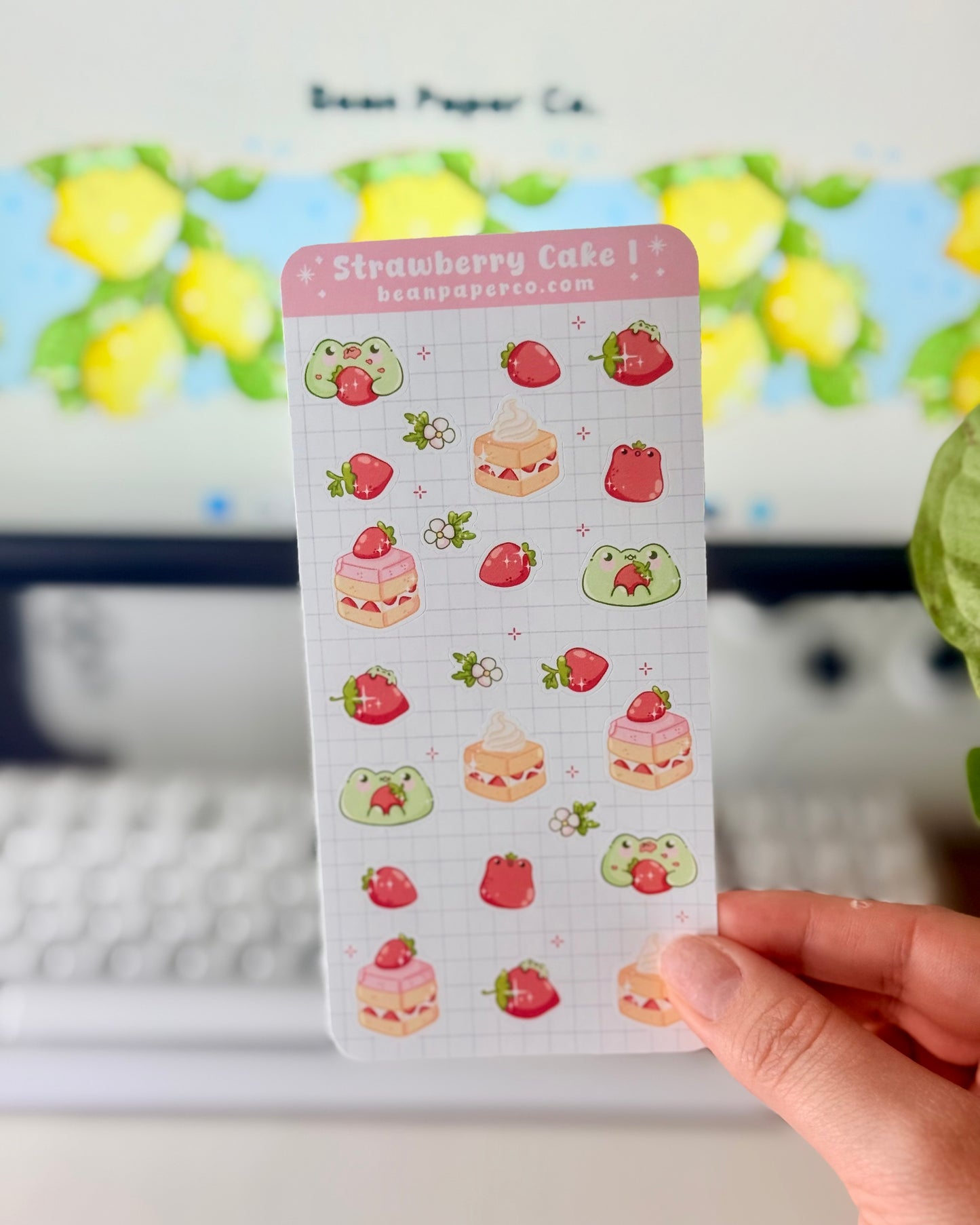 “Strawberry Cake frog sticker sheet featuring cute green frogs, strawberries, strawberry flowers, and layered cake slice on a light grid background.”