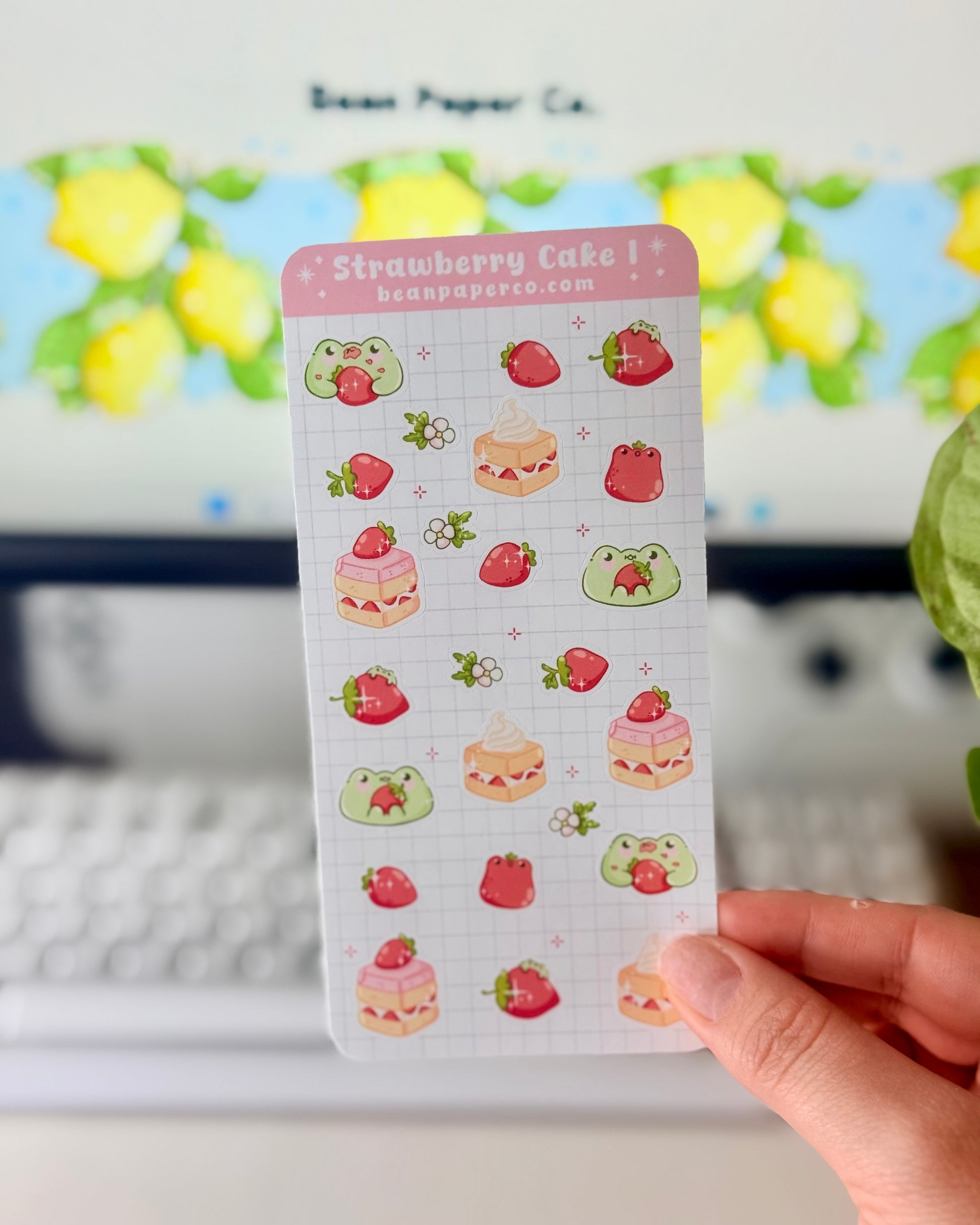 “Strawberry Cake frog sticker sheet featuring cute green frogs, strawberries, strawberry flowers, and layered cake slice on a light grid background.”