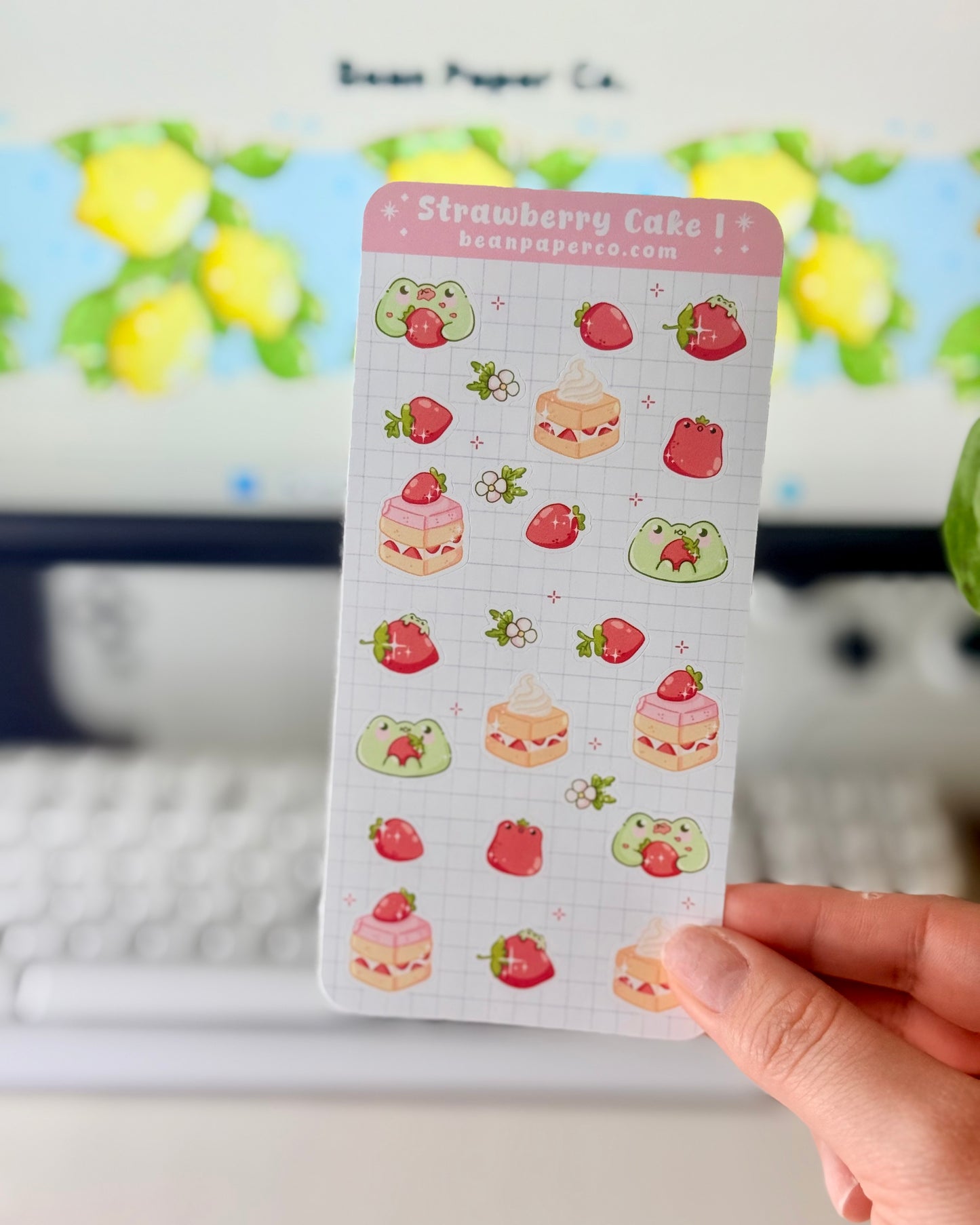 “Strawberry Cake frog sticker sheet featuring cute green frogs, strawberries, strawberry flowers, and layered cake slice on a light grid background.”