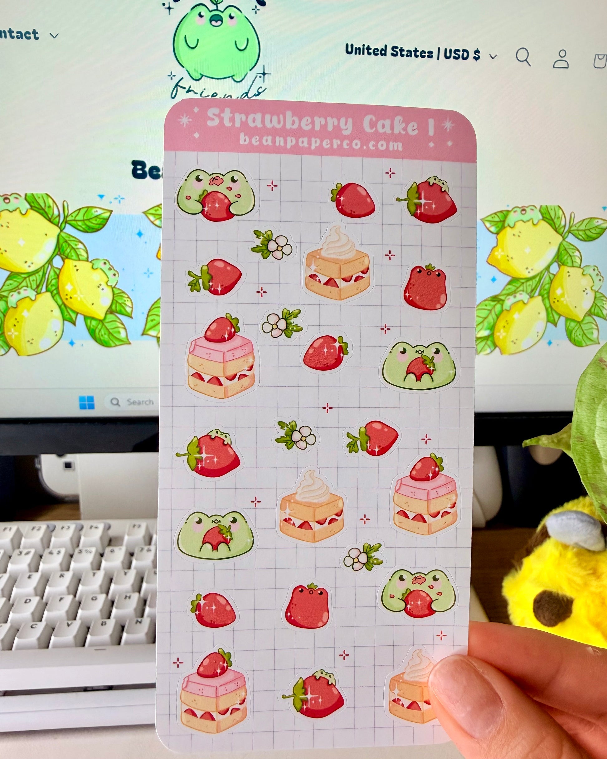 “Strawberry Cake frog sticker sheet featuring cute green frogs, strawberries, strawberry flowers, and layered cake slice on a light grid background.”