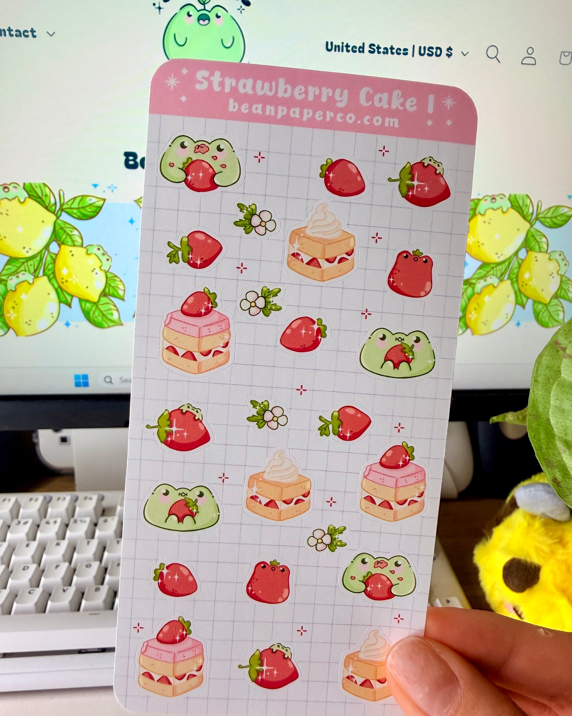 “Strawberry Cake frog sticker sheet featuring cute green frogs, strawberries, strawberry flowers, and layered cake slice on a light grid background.”