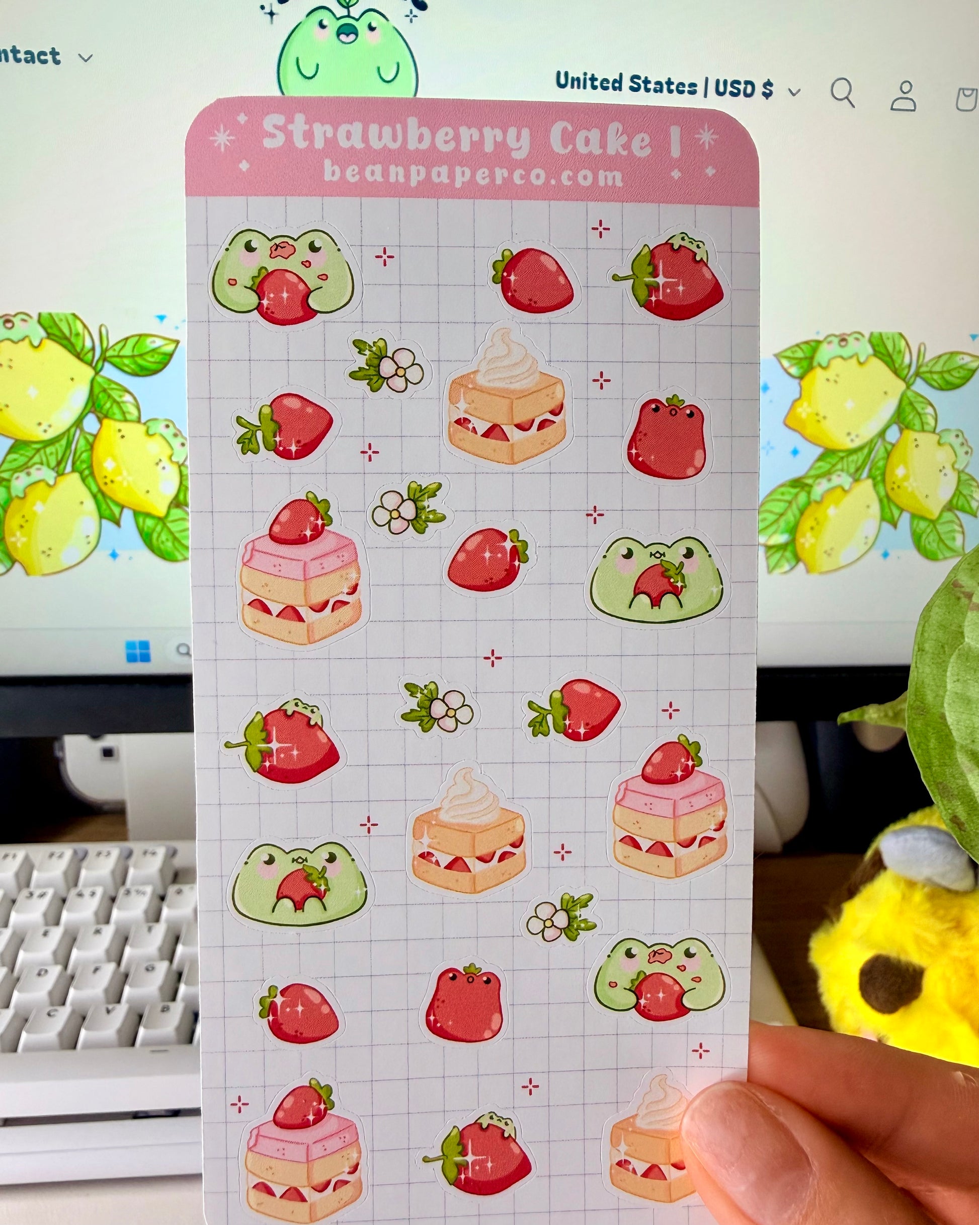 “Strawberry Cake frog sticker sheet featuring cute green frogs, strawberries, strawberry flowers, and layered cake slice on a light grid background.”