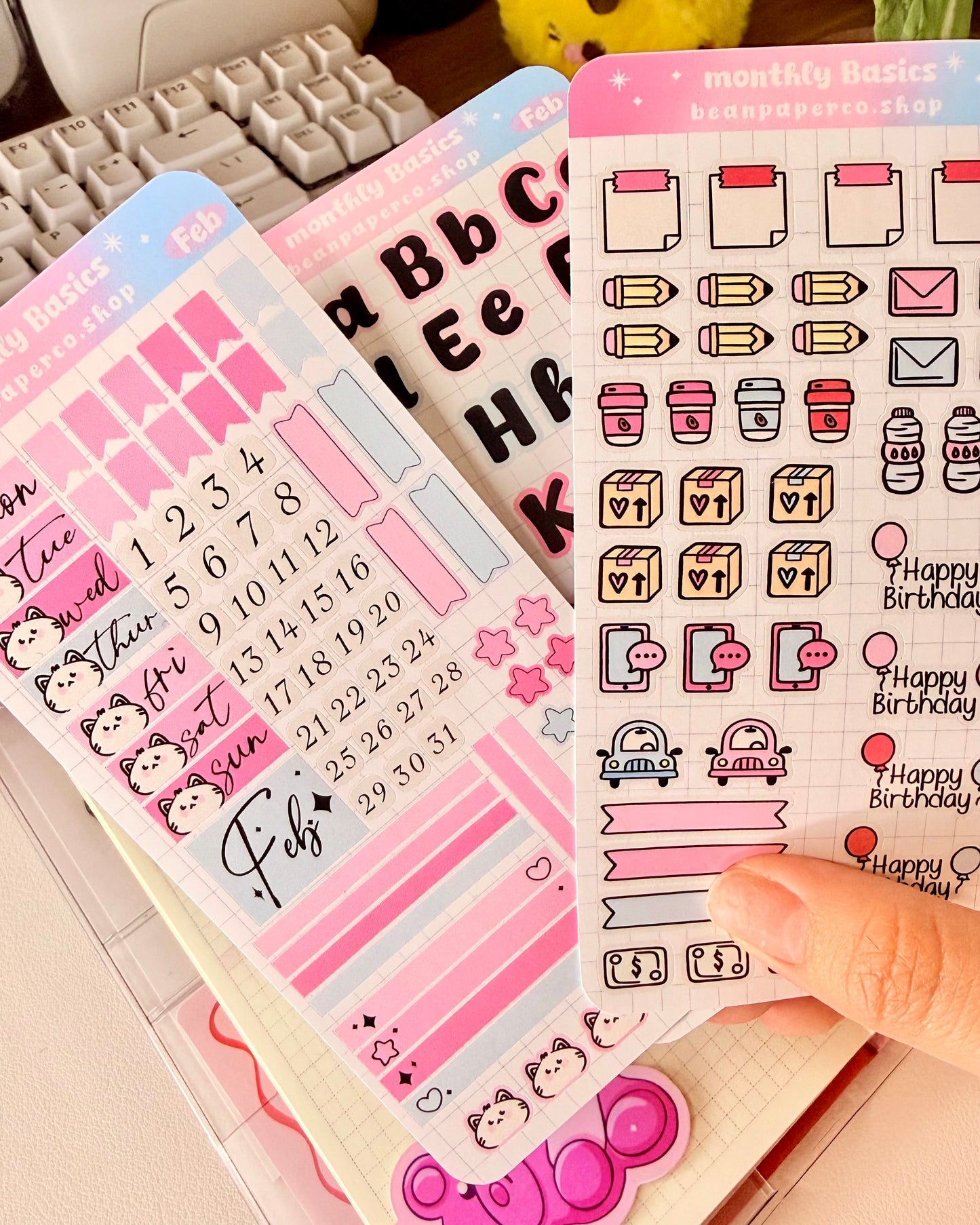 Hobonichi Weeks February Monthly Planner Sticker Kit featuring coffee cups, mail envelopes, package boxes, cars, water bottles, pencils, and birthday balloon stickers in pastel pink and blue.