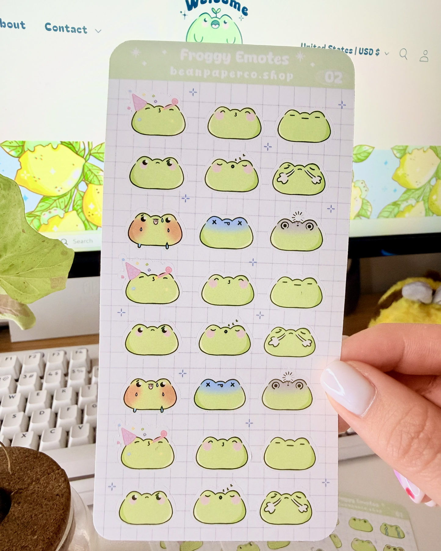 Cute Frog Emote Planner Stickers Vol. 2 featuring cute green frog faces with party hat, blushing, sleepy, angry, shocked, and fainting expressions on a light grid background.”