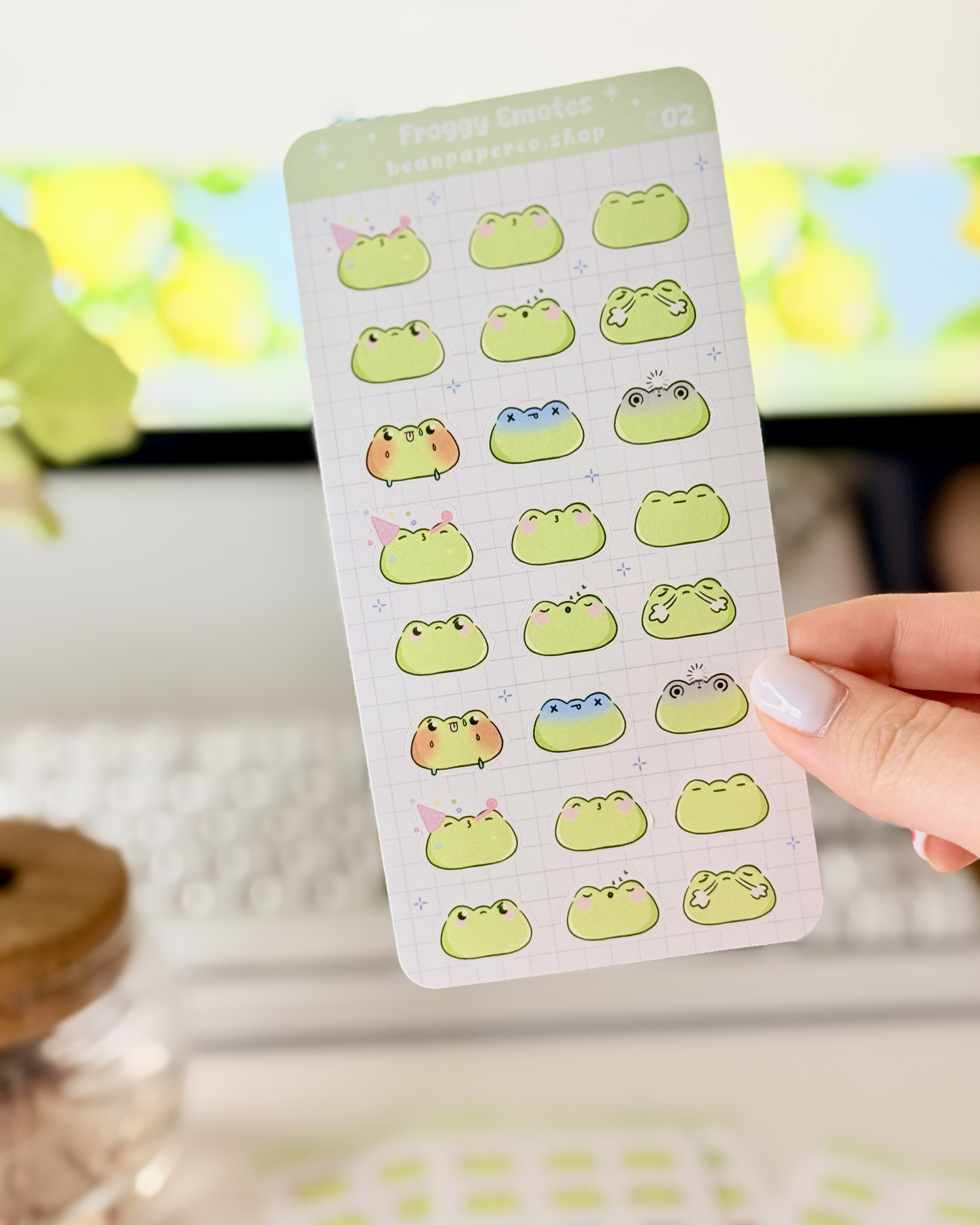 Cute Frog Emote Planner Stickers Vol. 2 featuring cute green frog faces with party hat, blushing, sleepy, angry, shocked, and fainting expressions on a light grid background.”