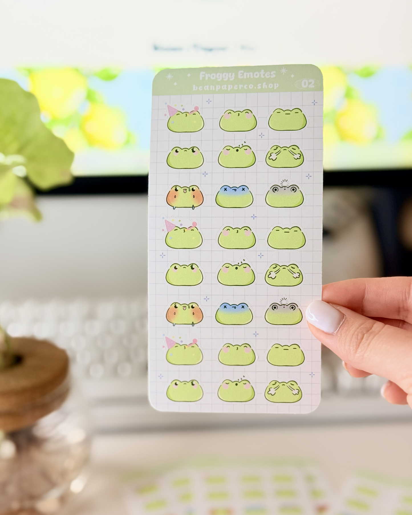 Cute Frog Emote Planner Stickers Vol. 2 featuring cute green frog faces with party hat, blushing, sleepy, angry, shocked, and fainting expressions on a light grid background.”
