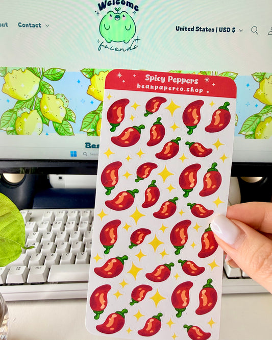 Cute Spicy Peppers Sticker Sheet held by a hand with a computer screen in the background.