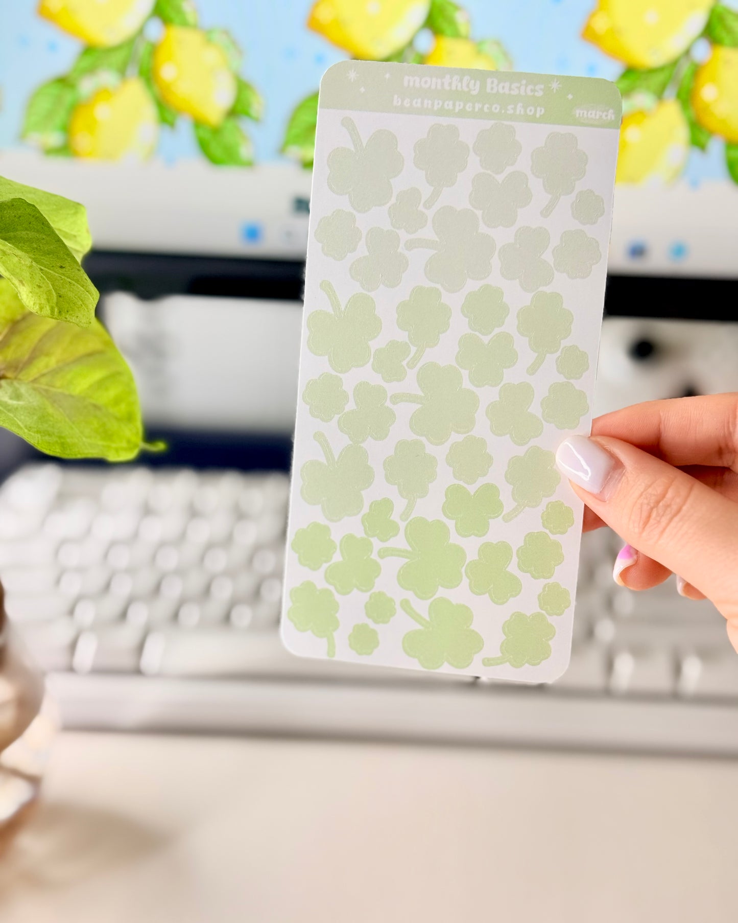 Cute March Clover Sticker Sheet held by hand featuring green ombre clovers.