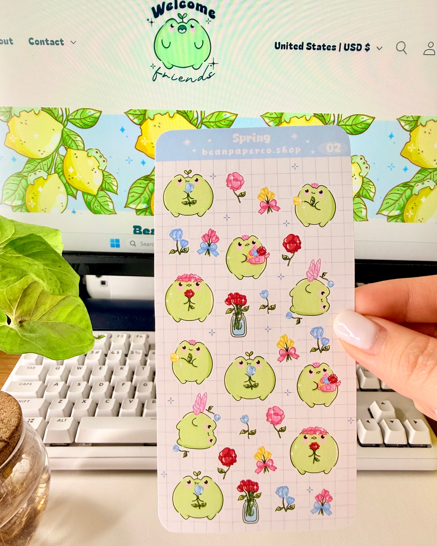 Hand holding Kawaii Spring Planner Stickers of frog characters and flowers.