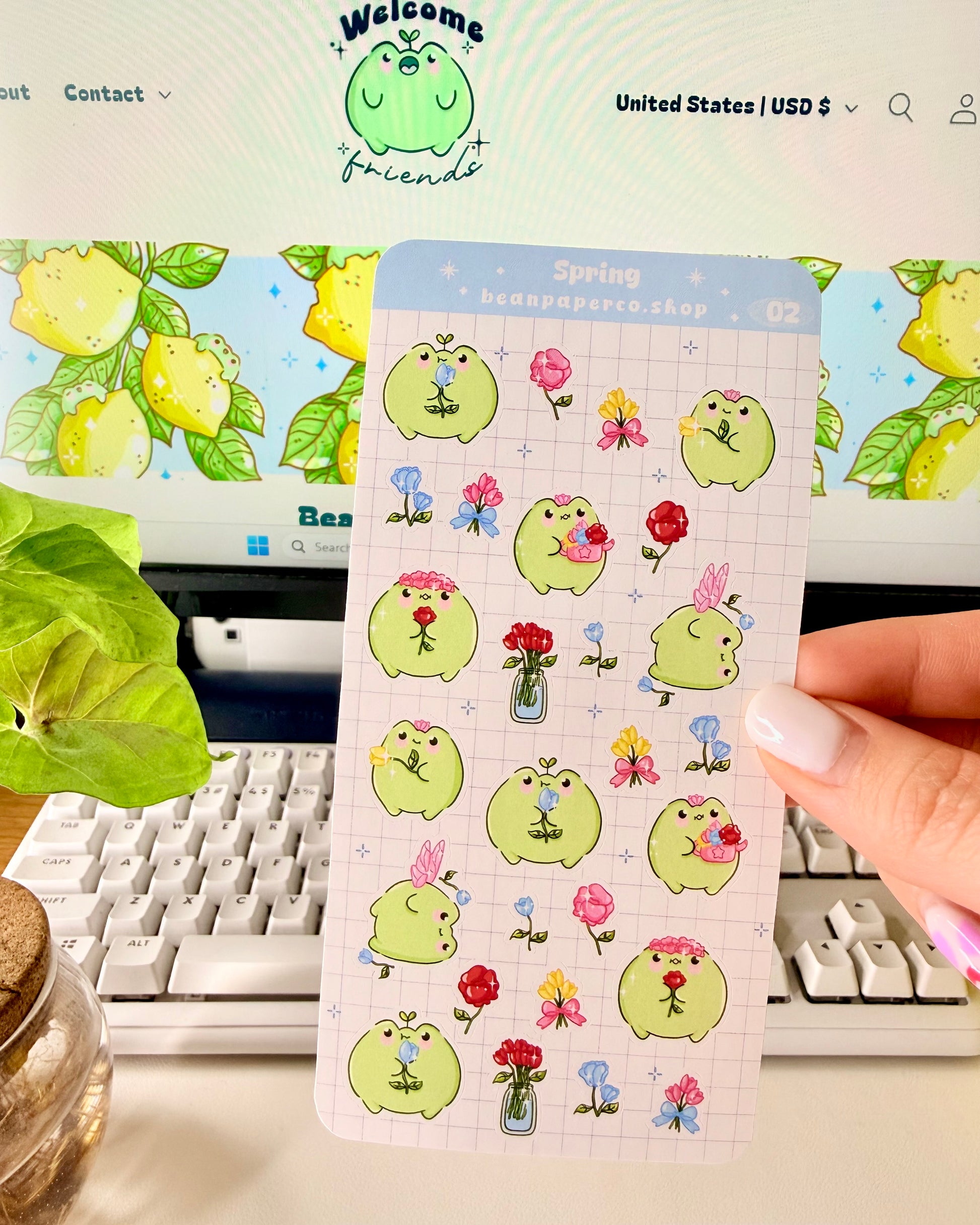 Hand holding Kawaii Spring Planner Stickers of frog characters and flowers.