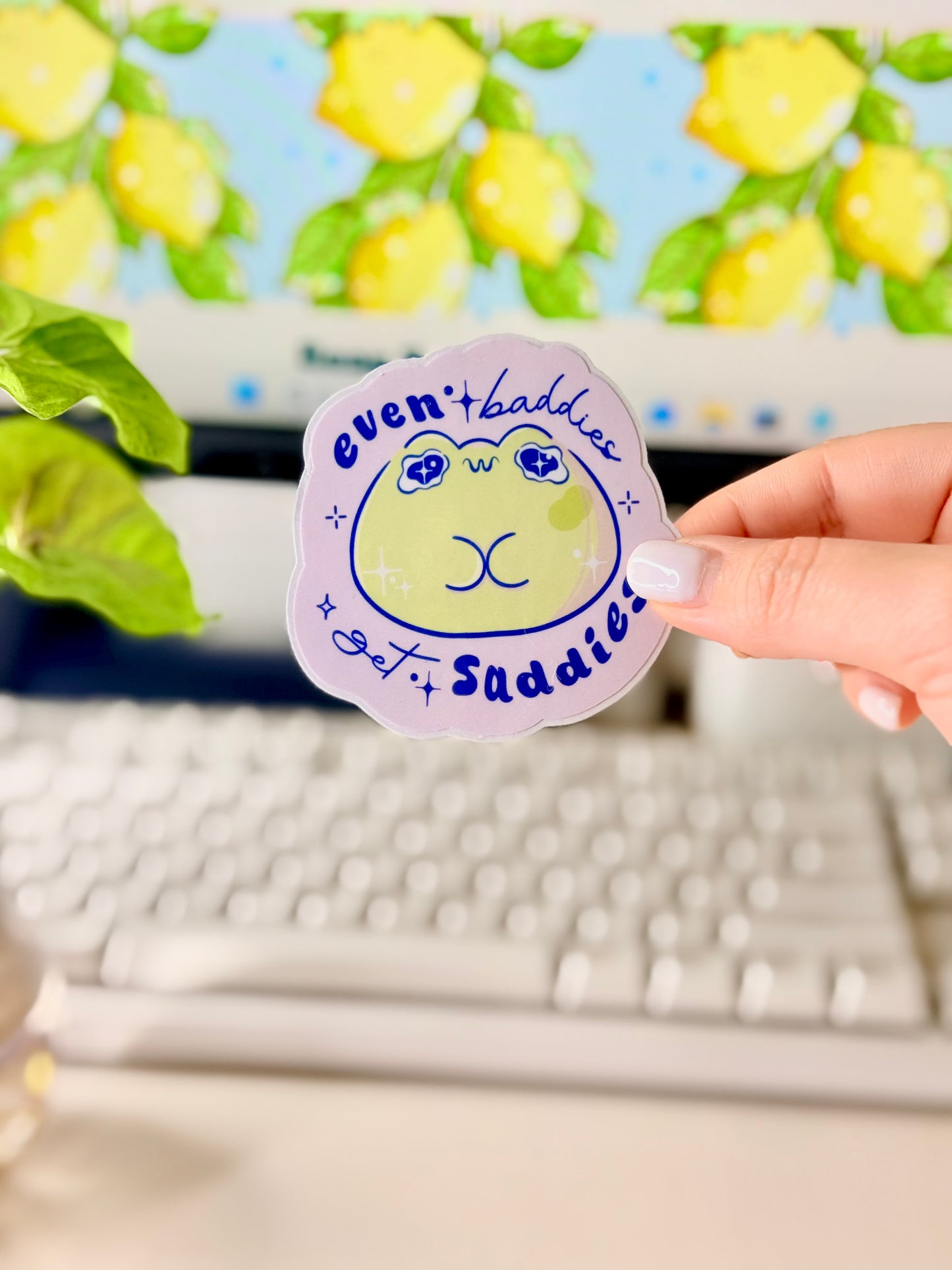 Even Baddies Get Saddies Vinyl Sticker with a cartoon frog character held by a hand in front of a computer screen.