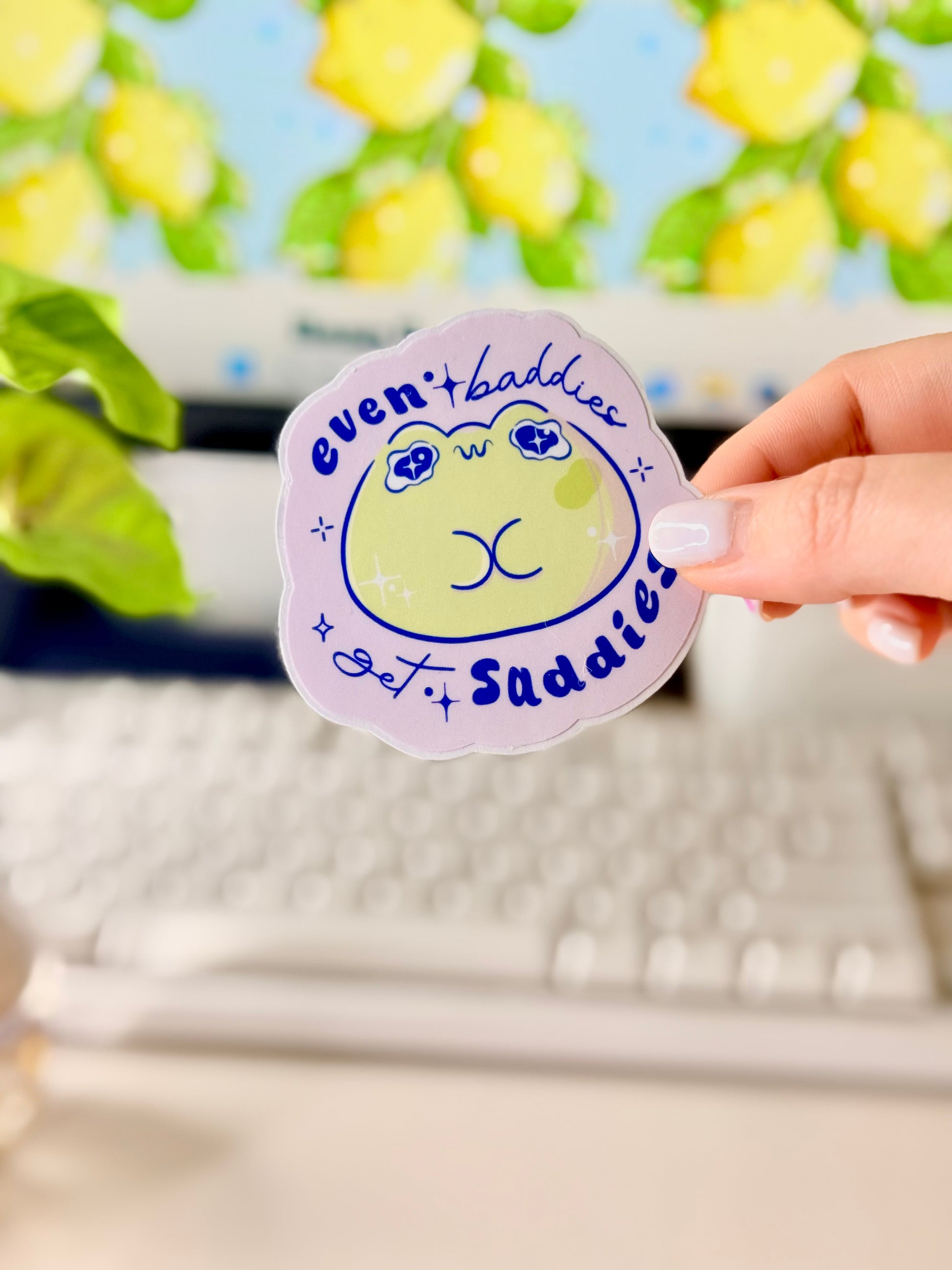 Even Baddies Get Saddies Vinyl Sticker with a cartoon frog character held by a hand in front of a computer screen.