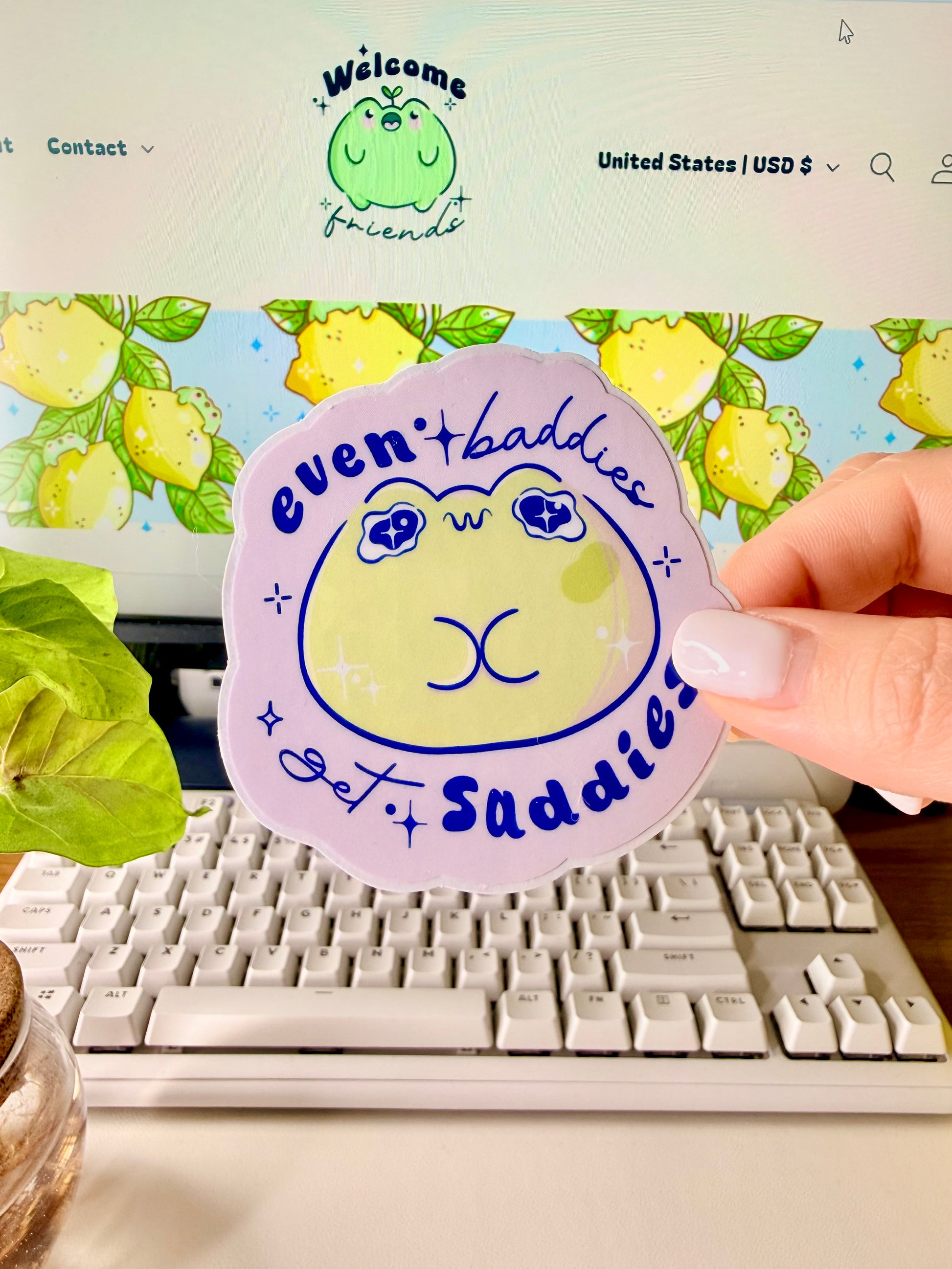 Even Baddies Get Saddies Vinyl Sticker with a cartoon frog character held by a hand in front of a computer screen.