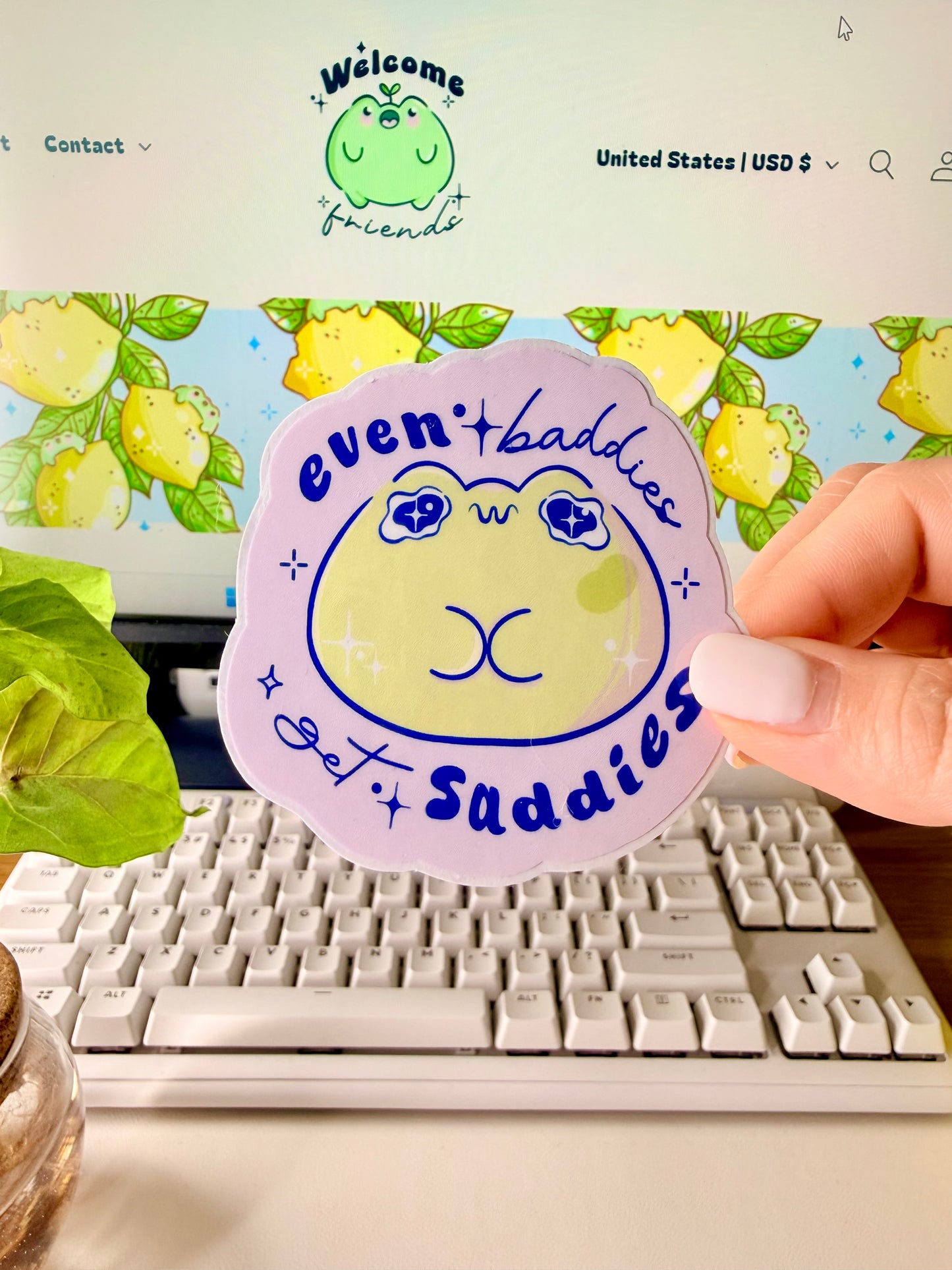 Even Baddies Get Saddies Vinyl Sticker with a cartoon frog character held by a hand in front of a computer screen.