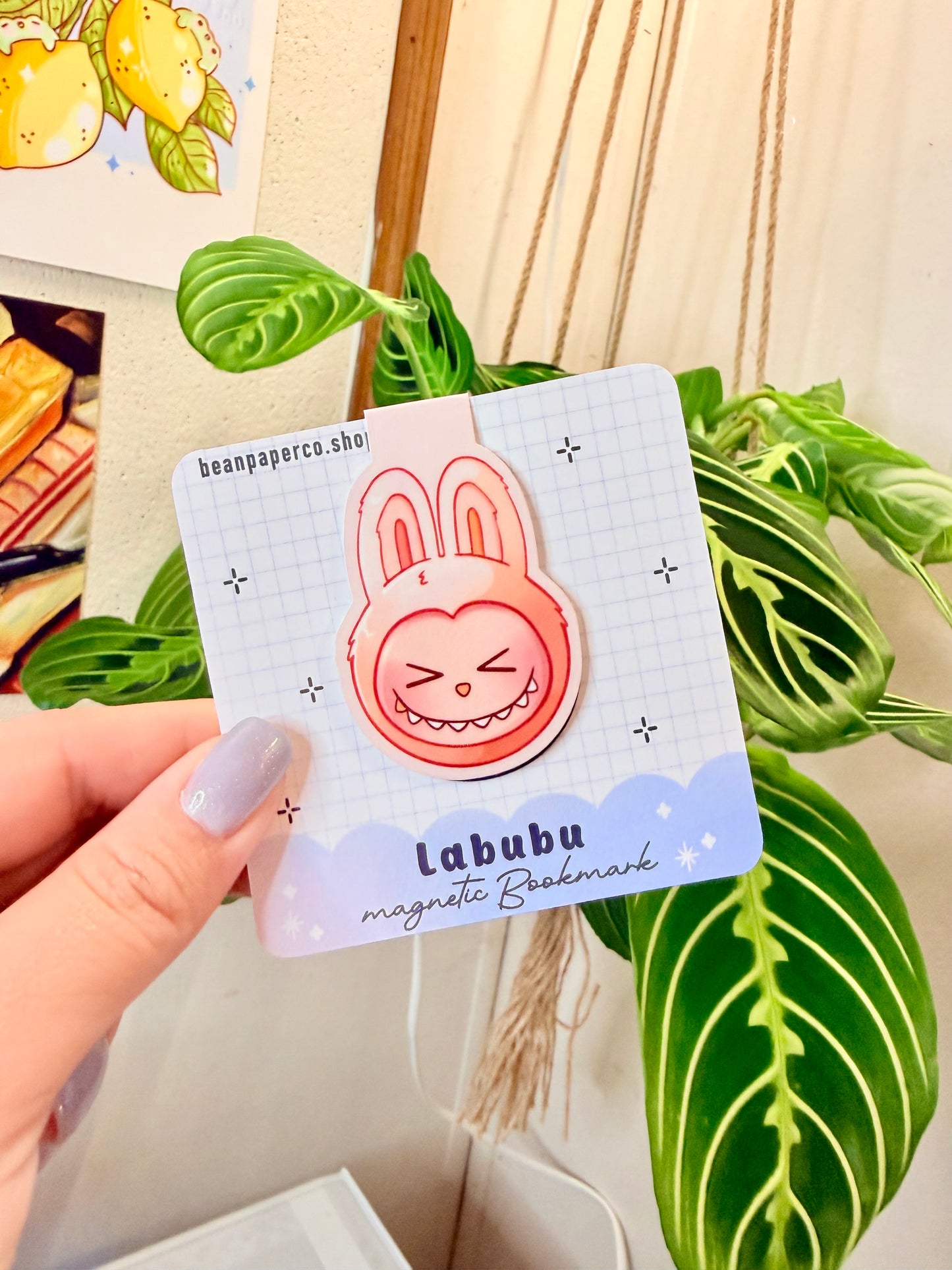 Labubu The Monsters Magnetic Bookmark held in hand with a plant background.