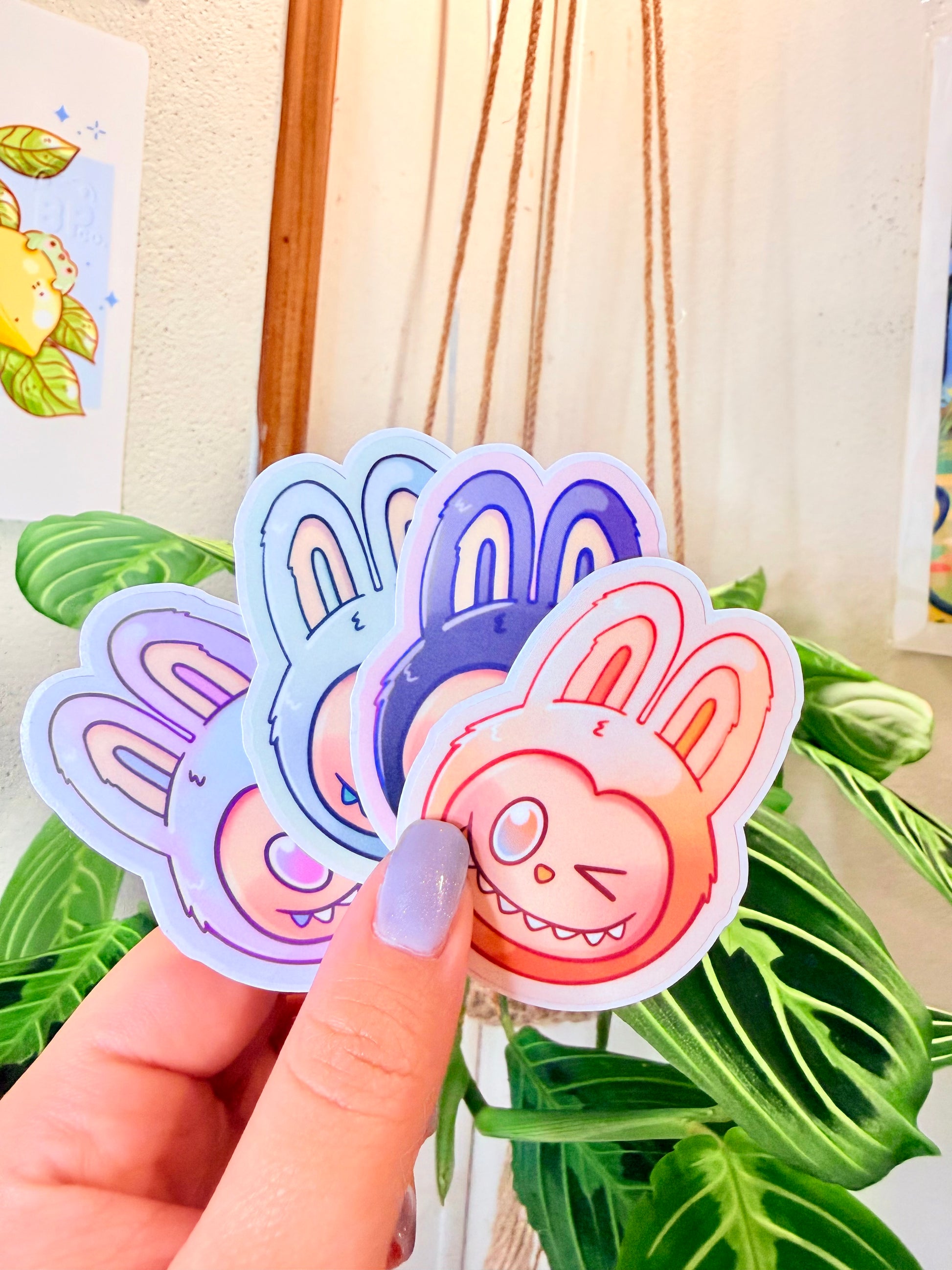 Labubu The Monsters Vinyl Sticker Pack held in hand, with a plant in the background.