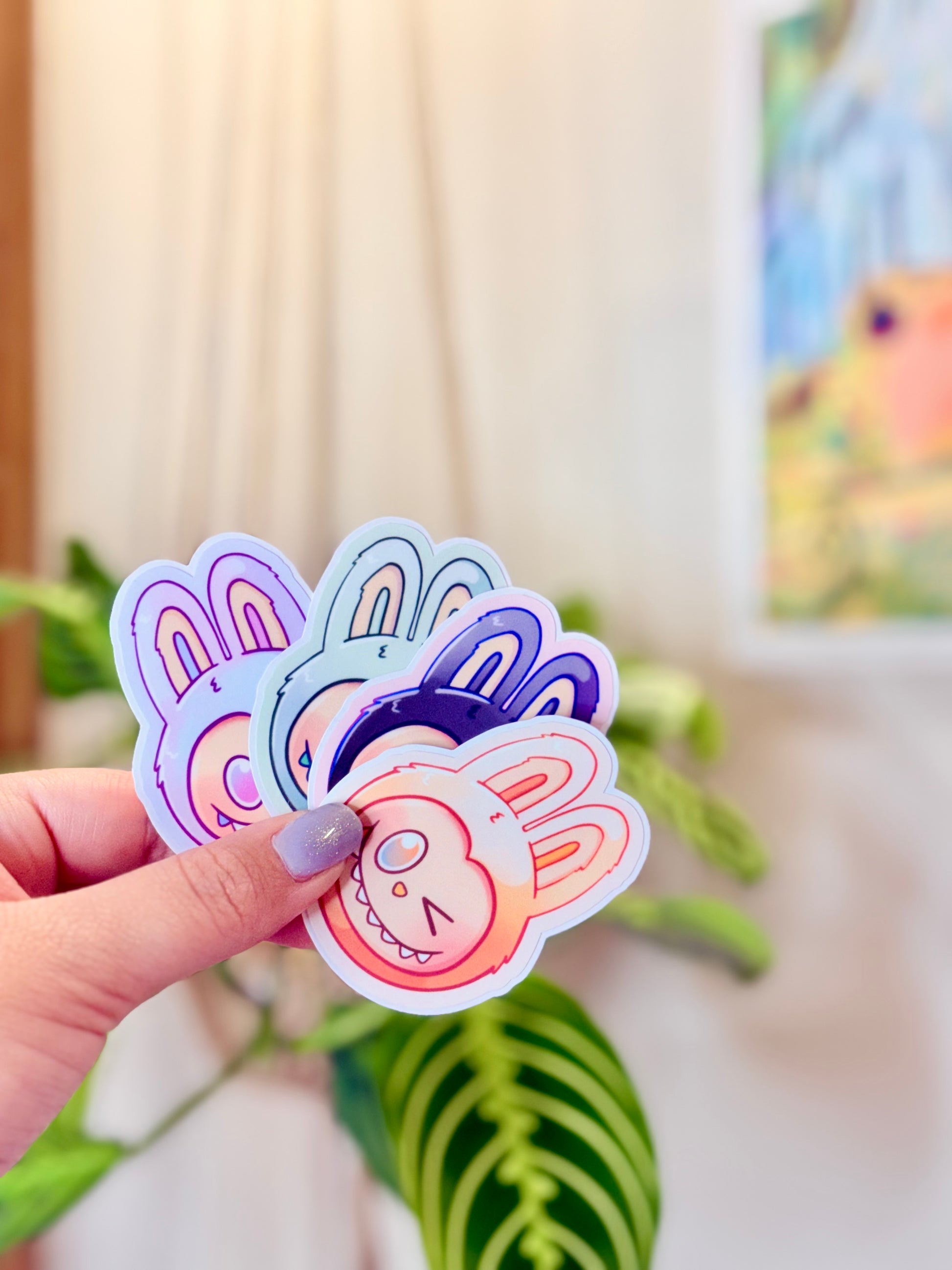 Labubu The Monsters Vinyl Sticker Pack held in hand, with a plant in the background.