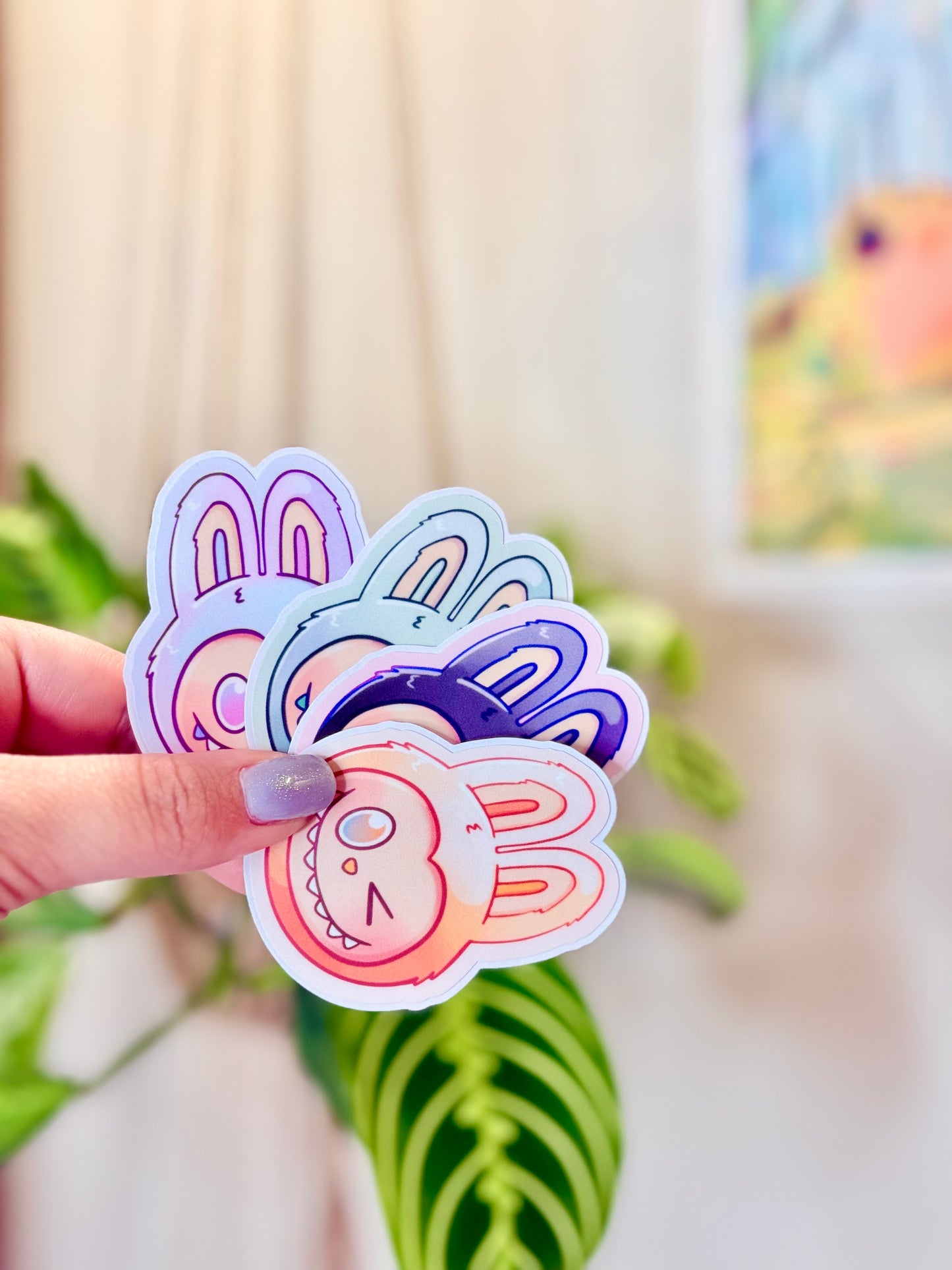 Labubu The Monsters Vinyl Sticker Pack held in hand, with a plant in the background.