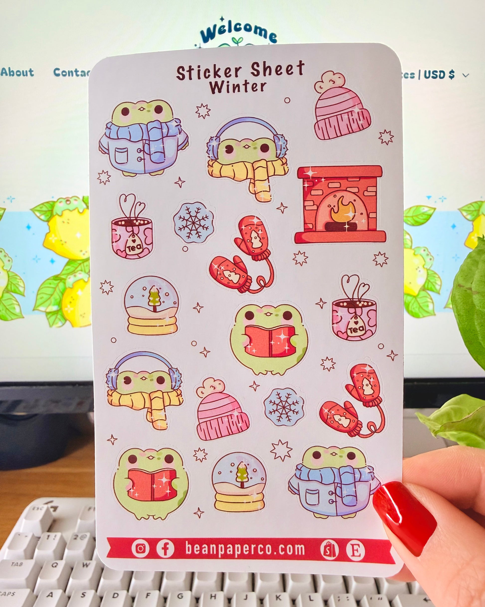 “Winter frog sticker sheet featuring frogs in scarves and earmuffs, mittens, snow globes, tea mugs, hats, snowflakes, and a cozy fireplace.”
