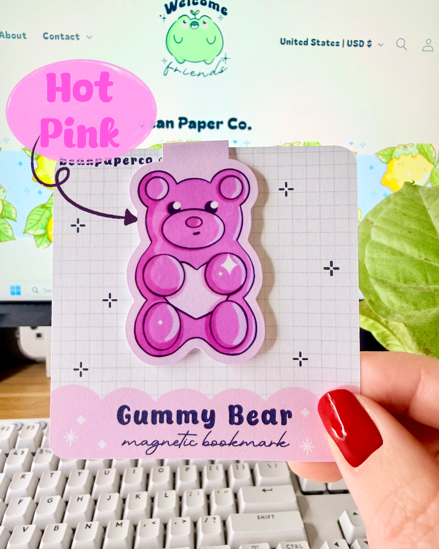 Red & Pink Gummy Bear Magnetic Bookmarks. Hot Pink Magnetic bookmark held in hand against blurred Bean Paper Co. website background.